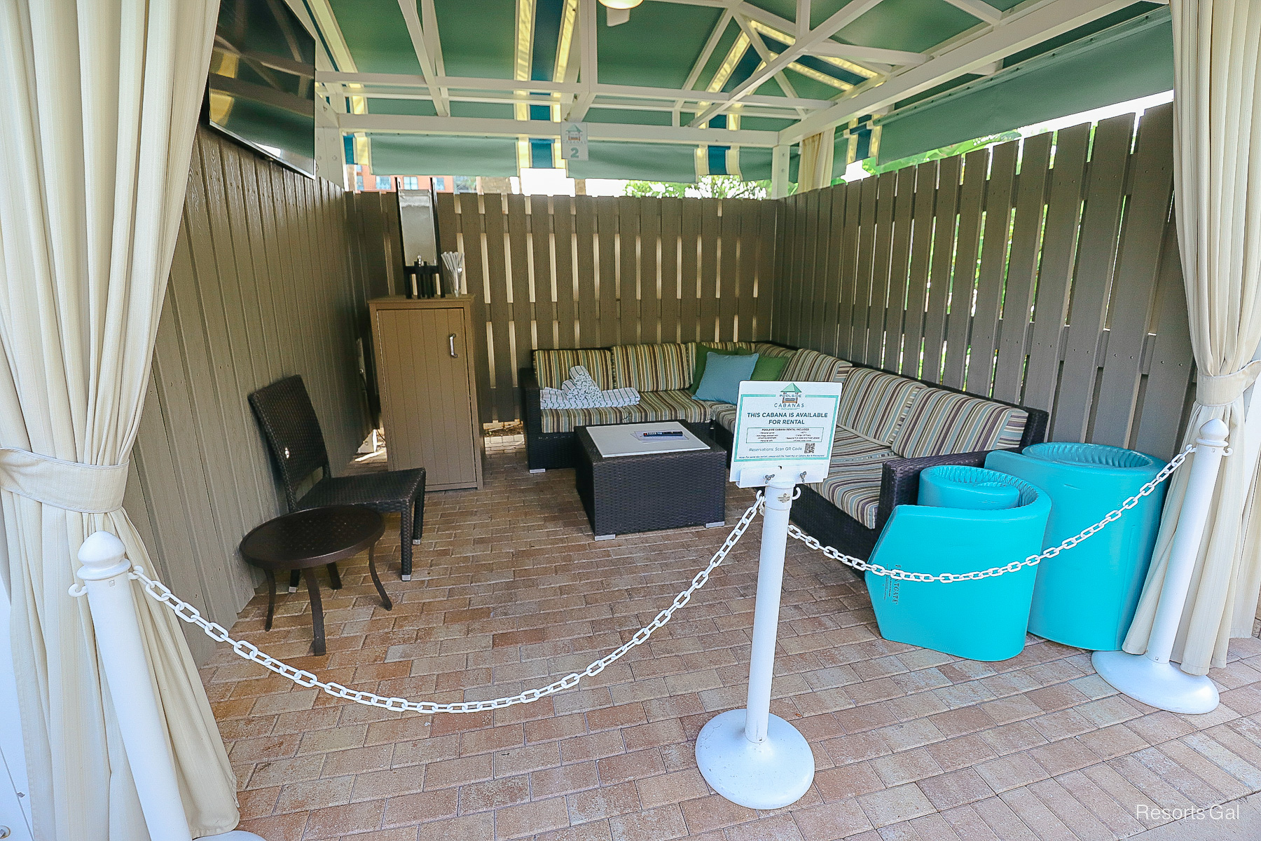 the inside of a cabana rentals with pool floats and an outdoor sectional 