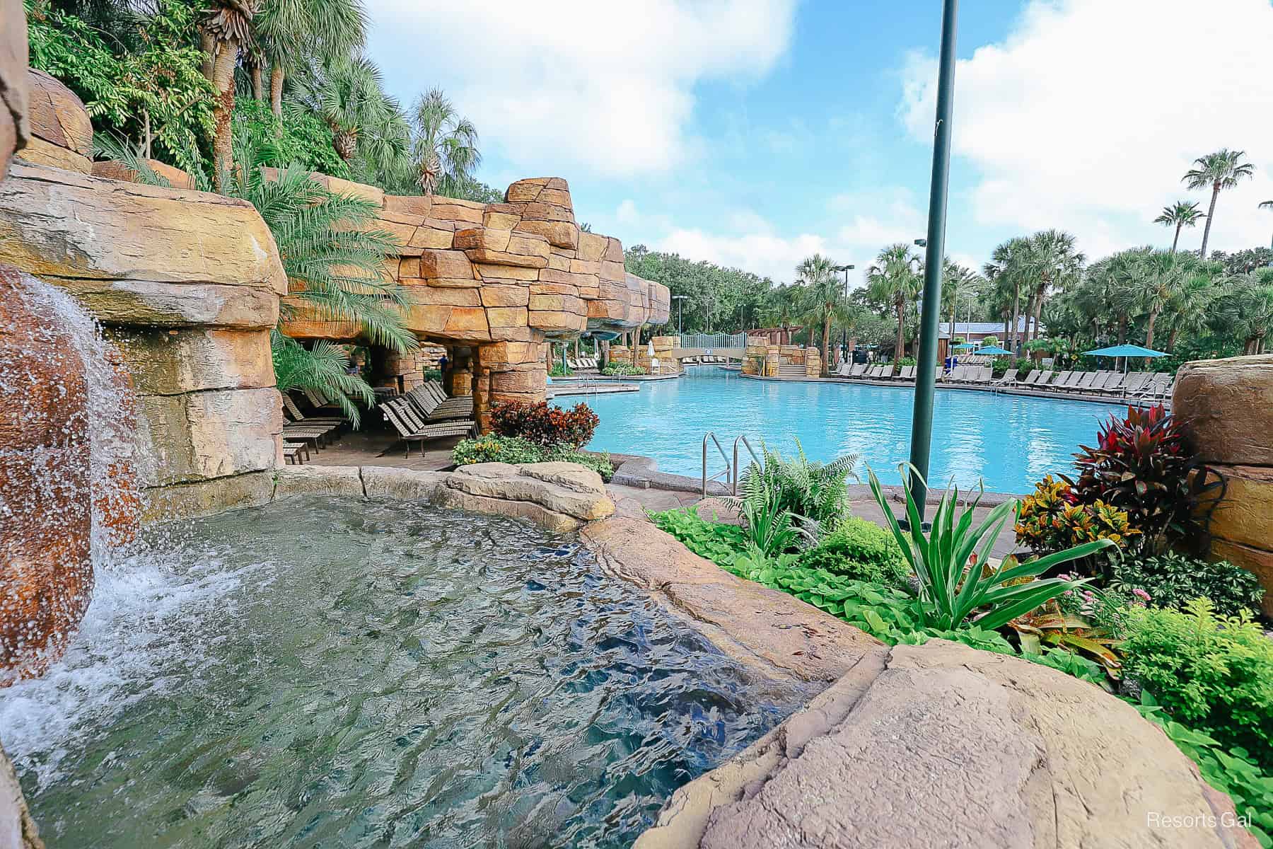 a waterfall features flows into a small pool of water that spills over into the pool 