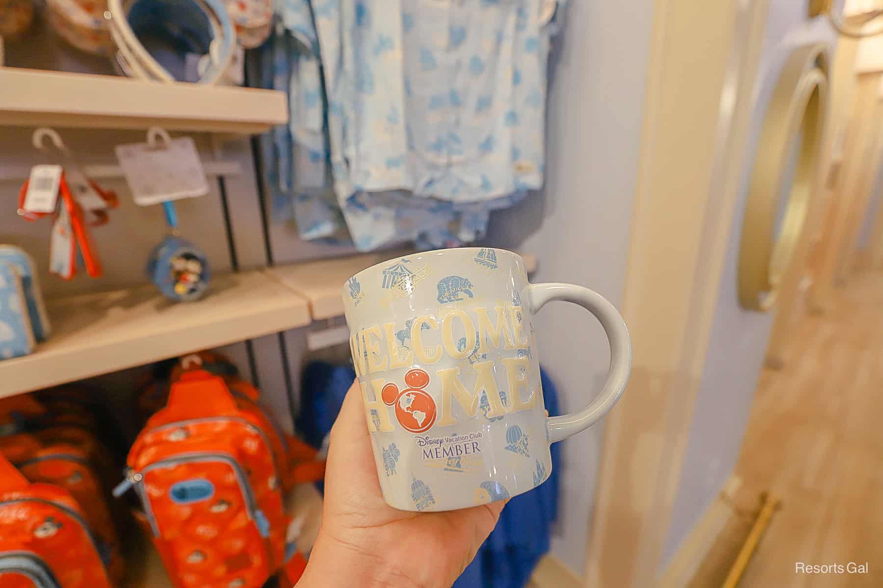 back side of the DVC mug says Welcome Home in blue, white, and light blue with icon print