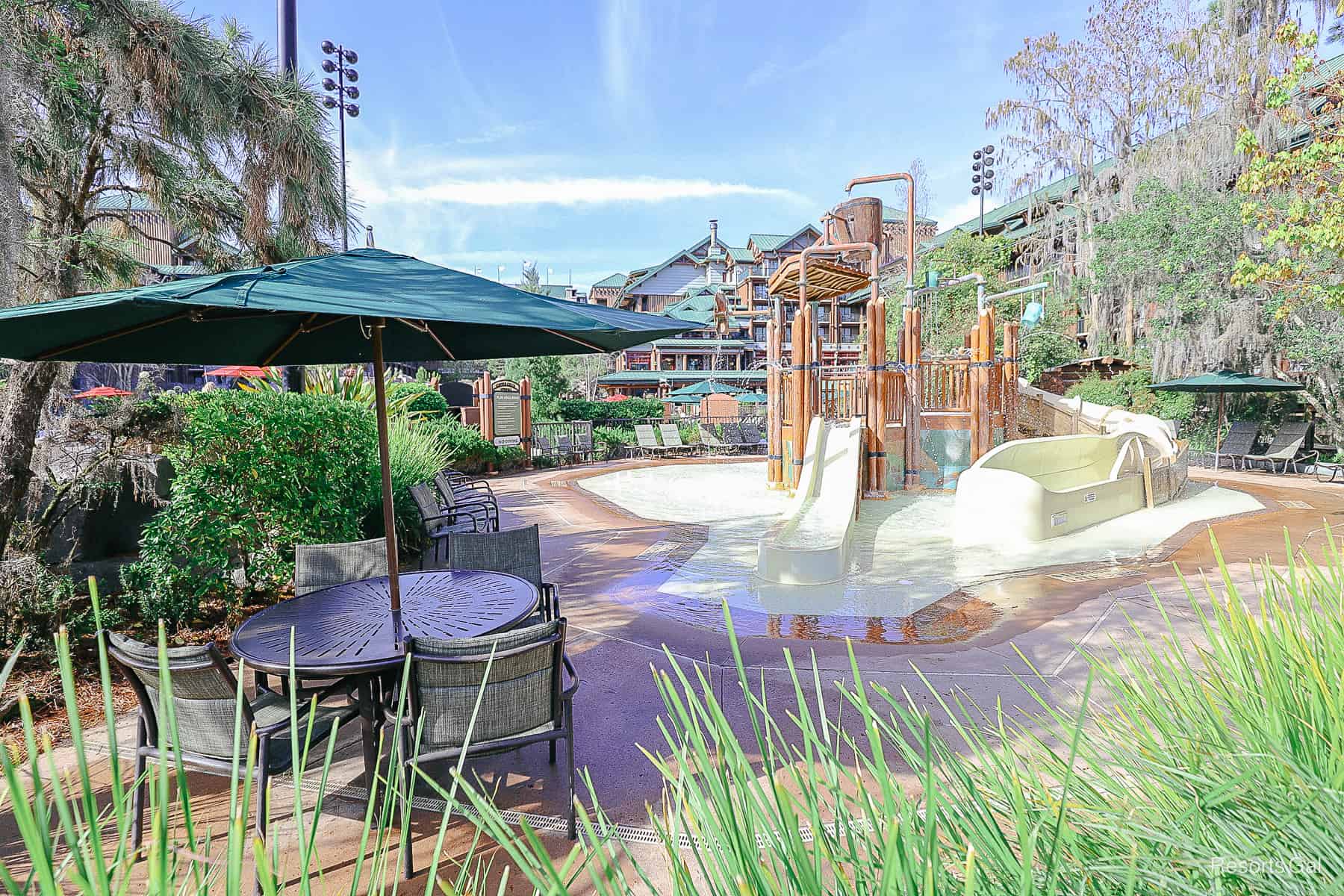 a table and chairs in the shade by the aquatic play area 