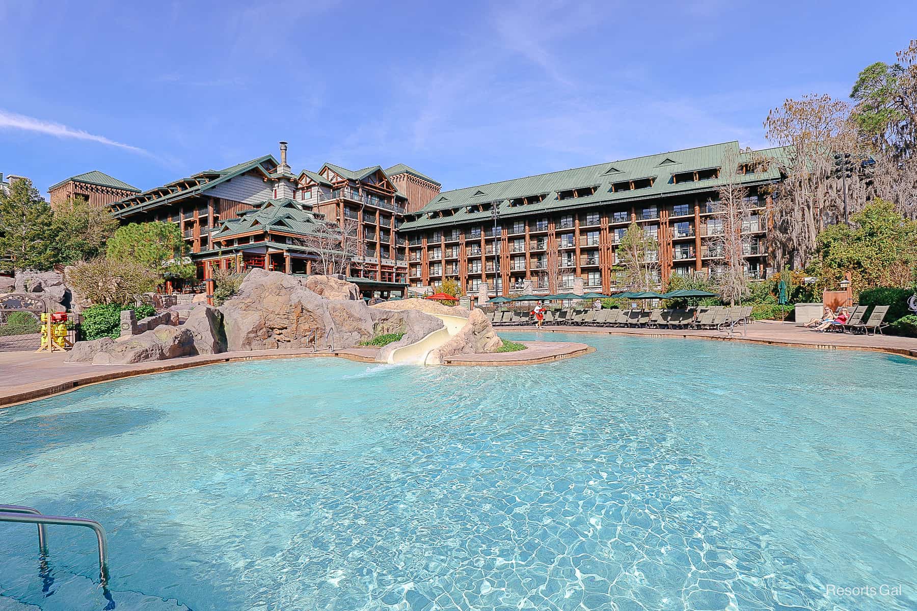 blue water of the pool with the brown Wilderness Lodge in the background 