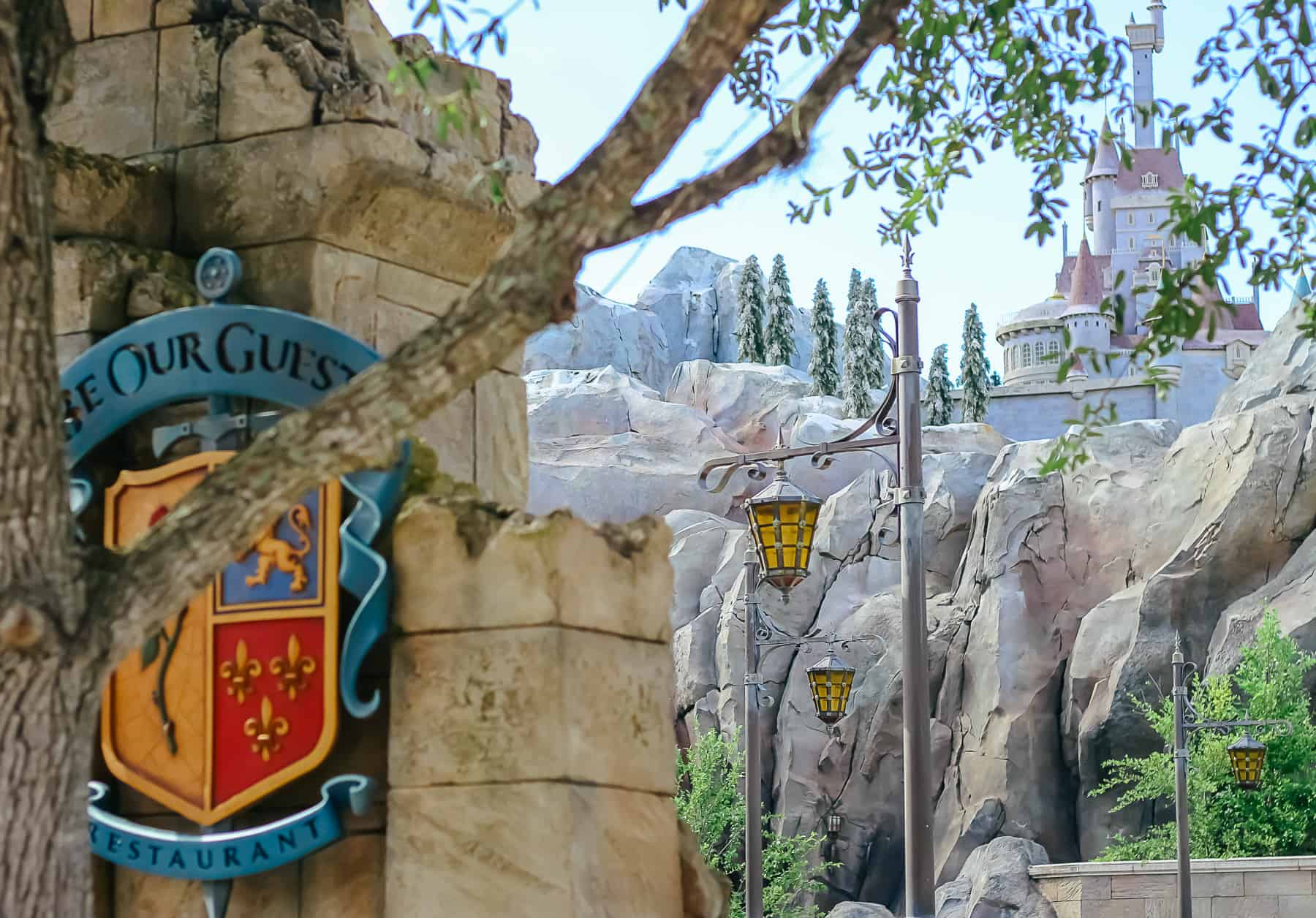 Be Our Guest sign with the Beast's castle in the distance 