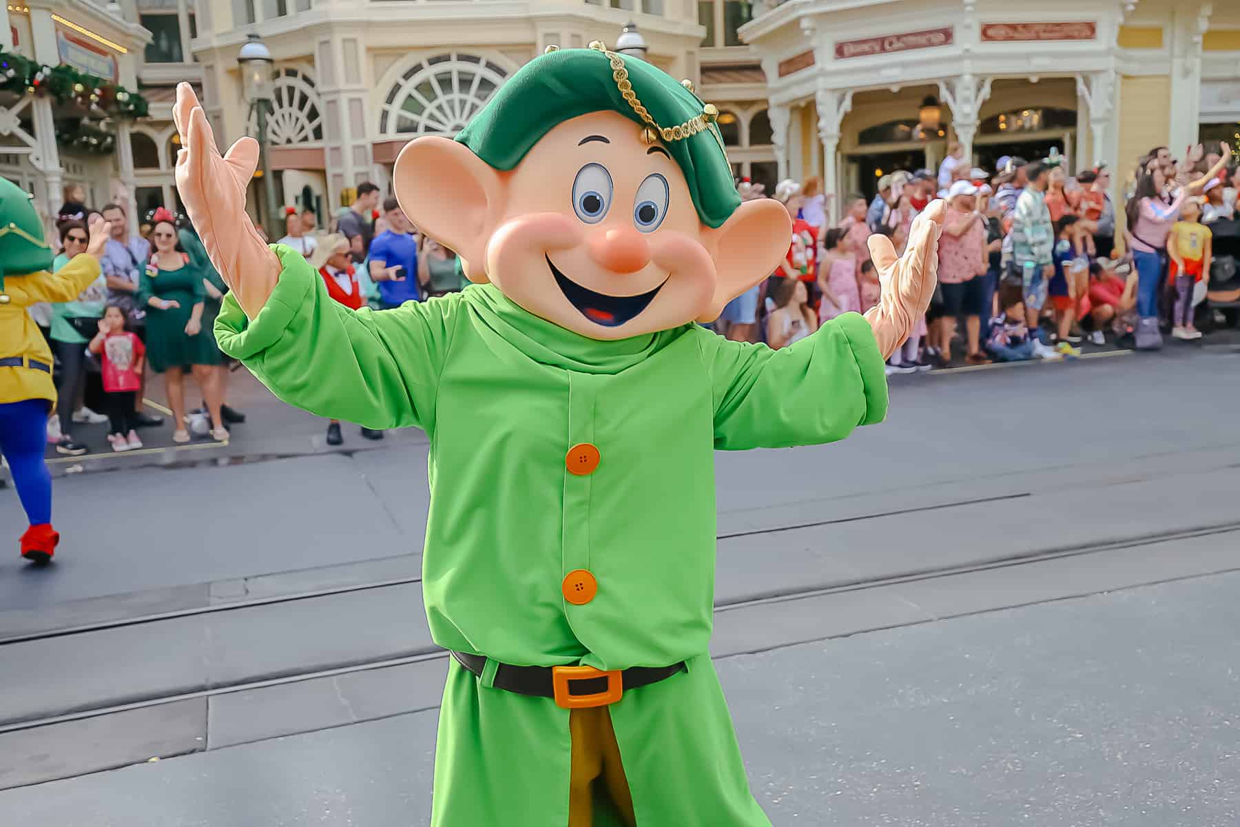 Dopey waves his hands in the air as he passes by on the parade route. 