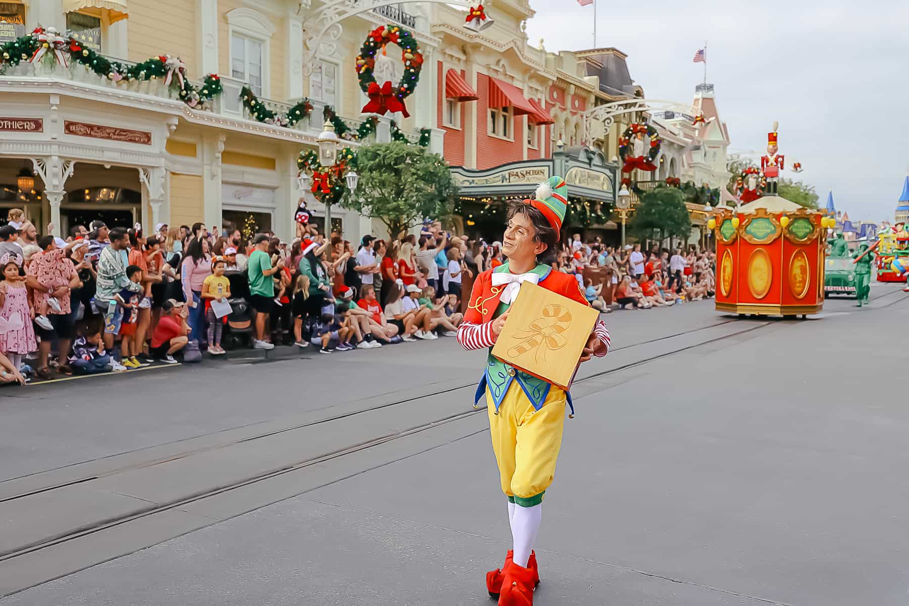 An elf carrying a block with a candy cane printed on it. 