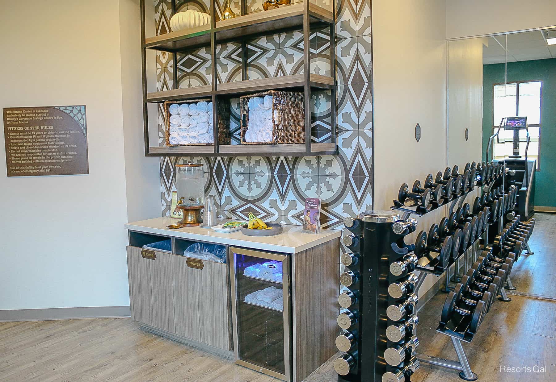 a display with fresh water, fruit, towels, and other amenities for guests using the gym 