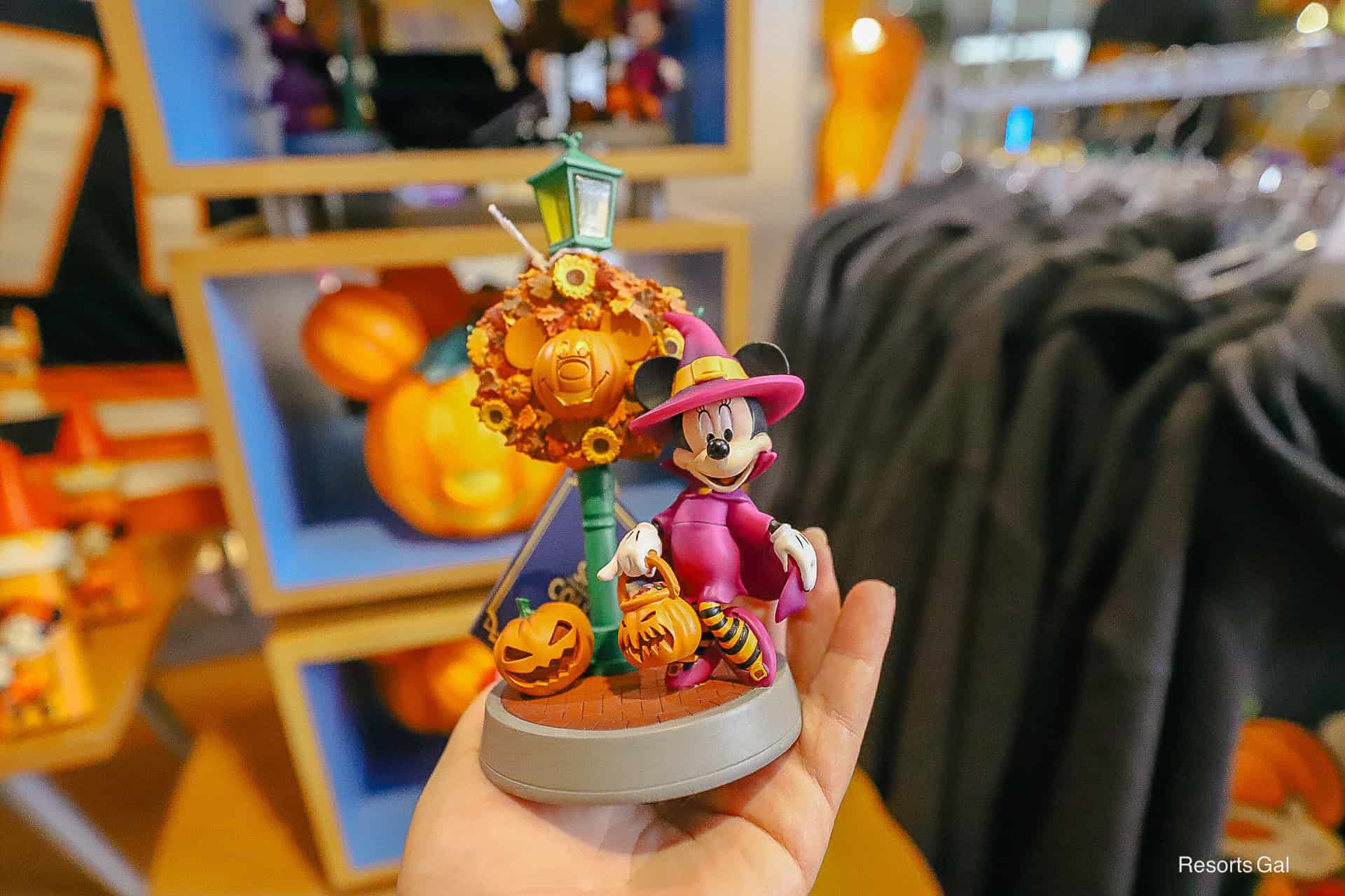 a collectible figurine featuring Minnie Mouse in a witch costume under a Mickey light pole