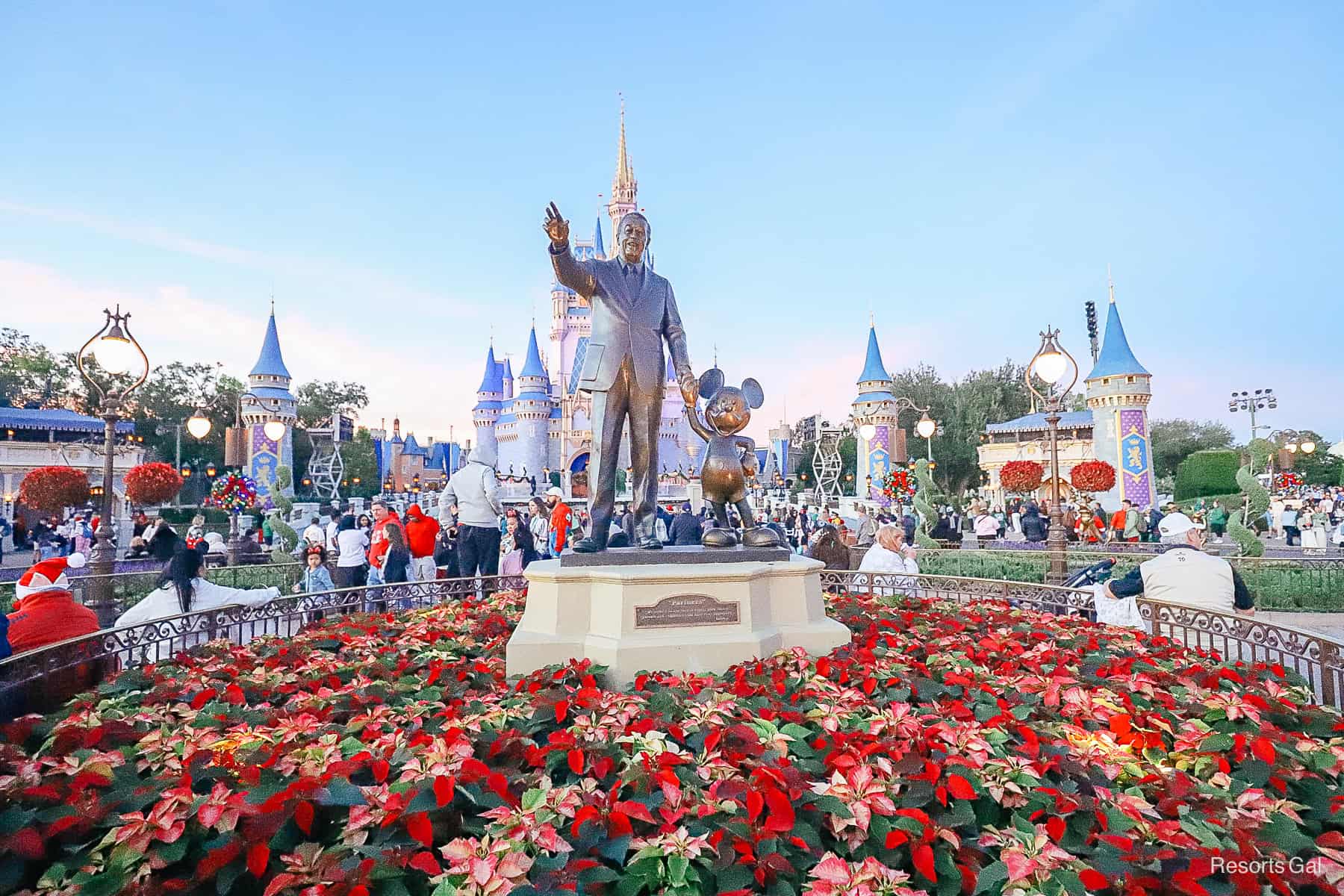 Magic Kingdom Partners Statue surrounded by poinsettias at Christmas 
