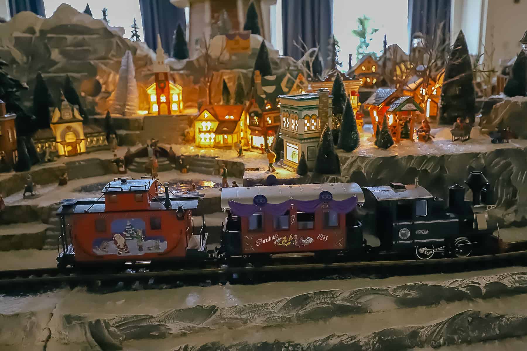 A miniature train with an engine, car, and a caboose on the train tracks.