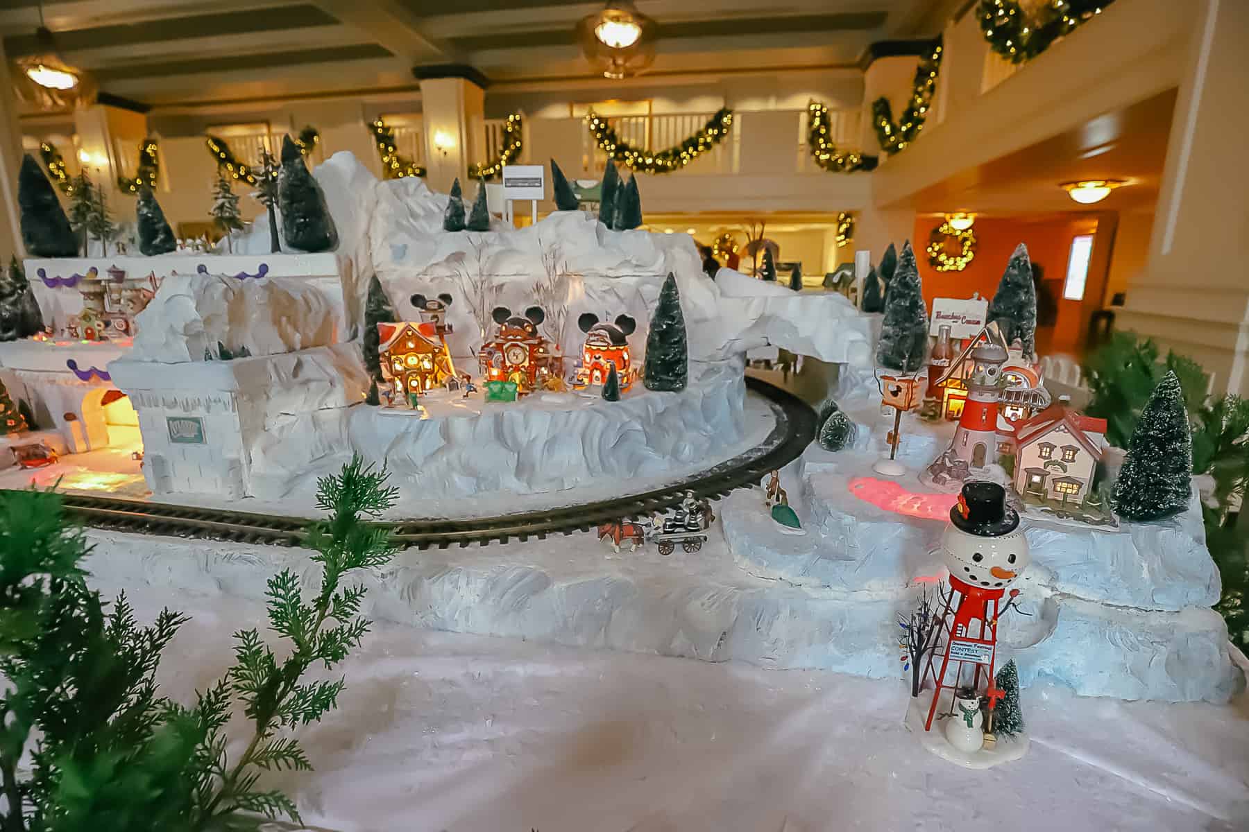 A closeup view of the Christmas village that shows a water tower decorated to look like a snowman. 