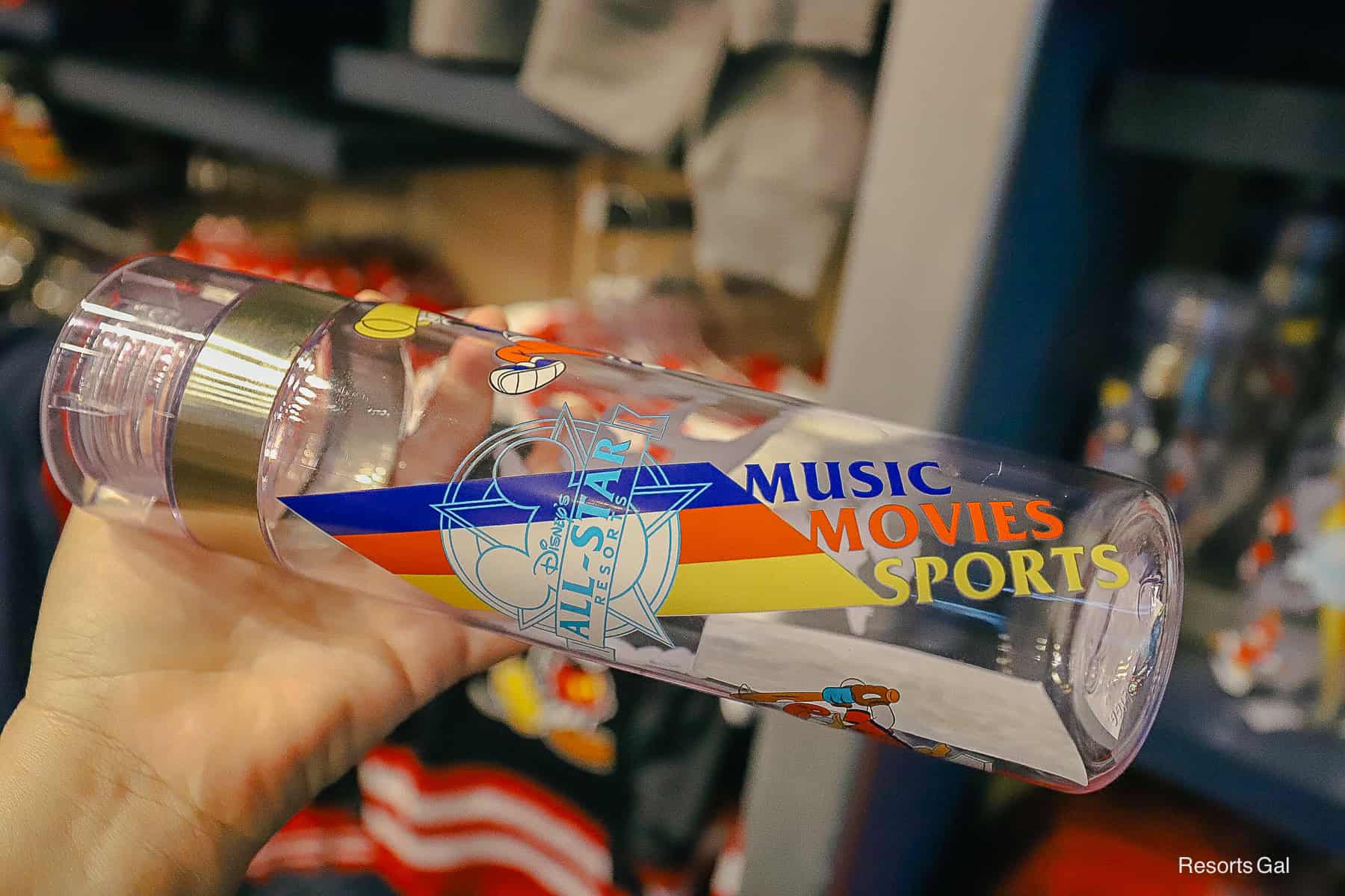 a hand holding a mug sideways so you can see the entire Music, Movies, and Sports logo 