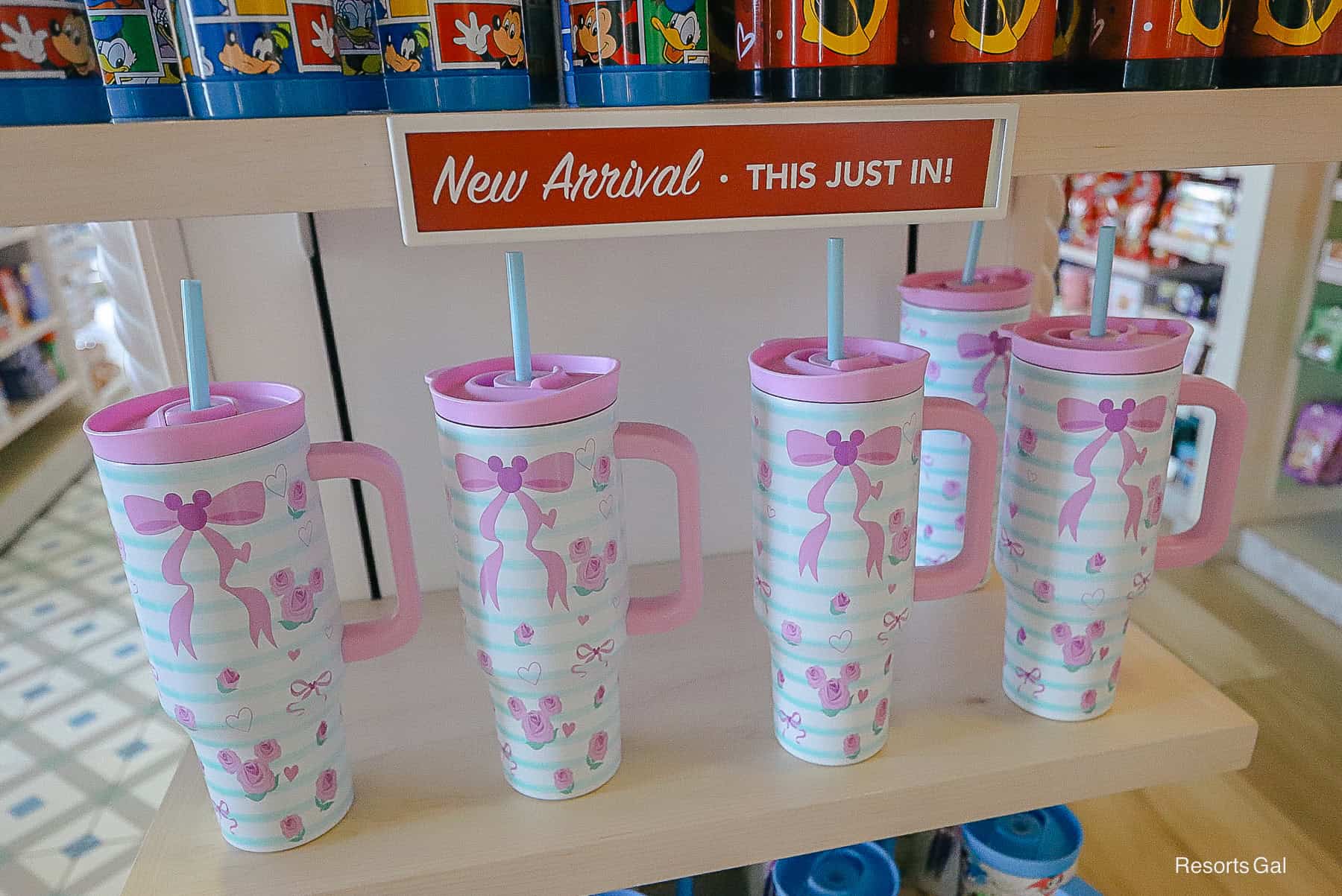 a display that says new arrival with a travel cup featuring Mickey Roses and pink bow patterns