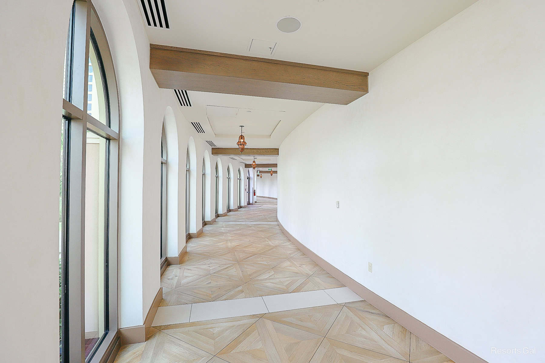 a long interior hallway with a light tile pattern