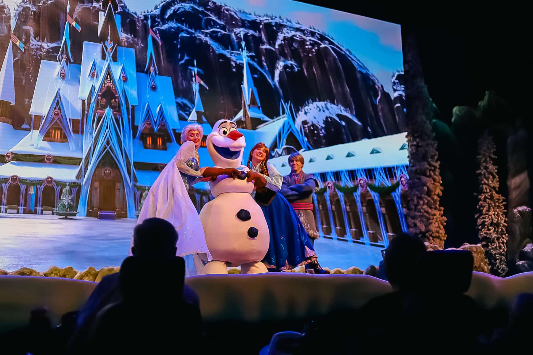 Anna and Elsa hugging Olaf on stage 