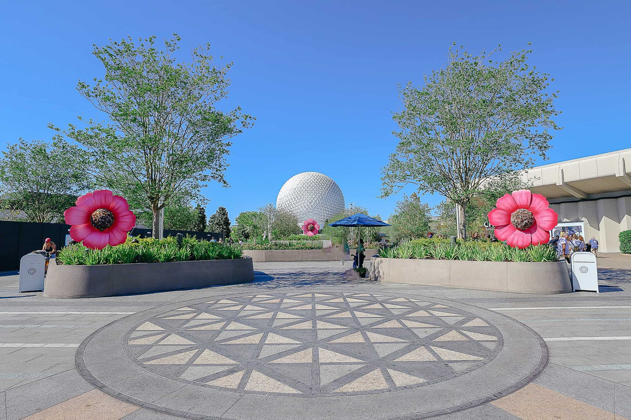 a medallion of Spaceship Earth in the newly opened area at Epcot with Spaceship Earth in the backdrop 