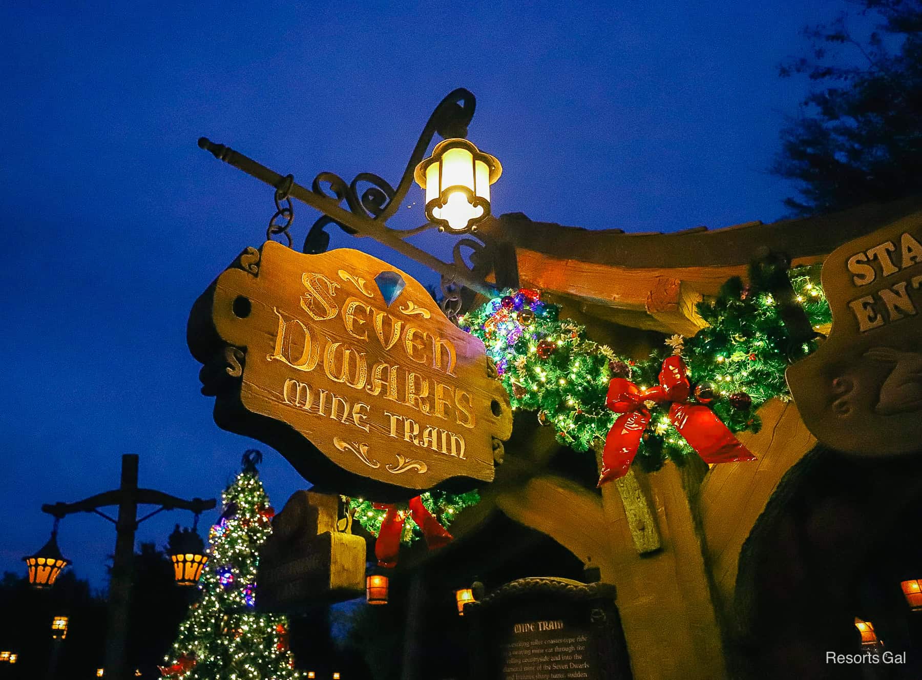 the Fantasyland attractions sign lit up at night 