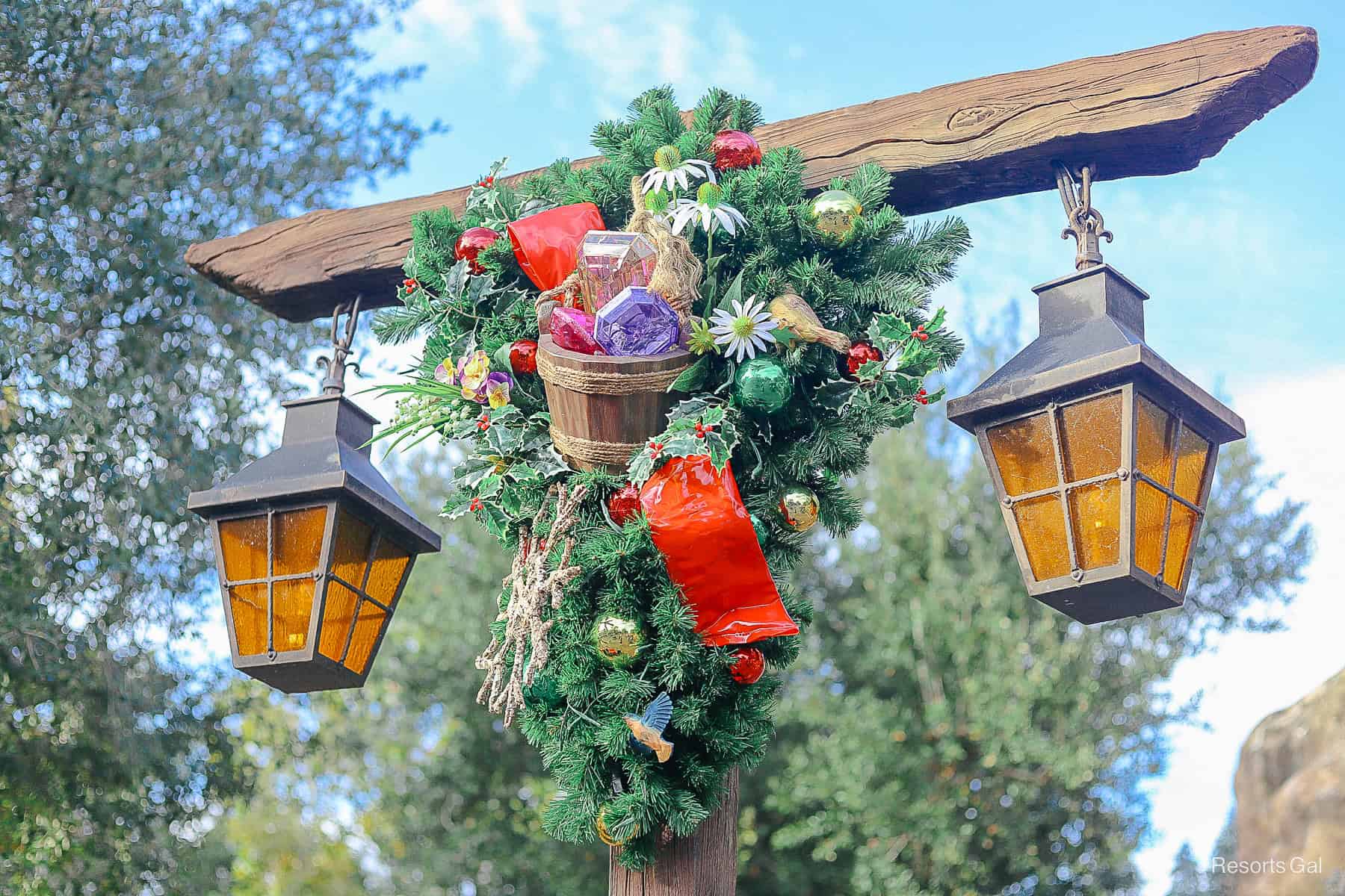 a lamp post with a holiday bough featuring a basket of jewels and a red bow 