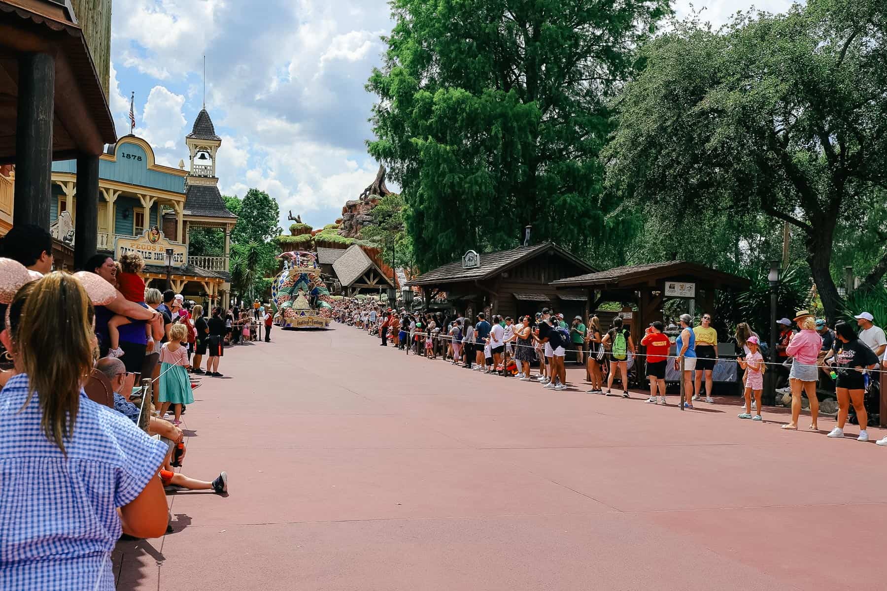 Shows guests waiting as the Festival of Fantasy Parade steps off from Frontierland. 