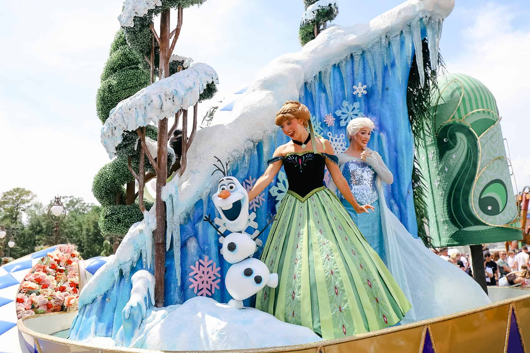Anna and Elsa ride together on a float in the Festival of Fantasy Parade. 