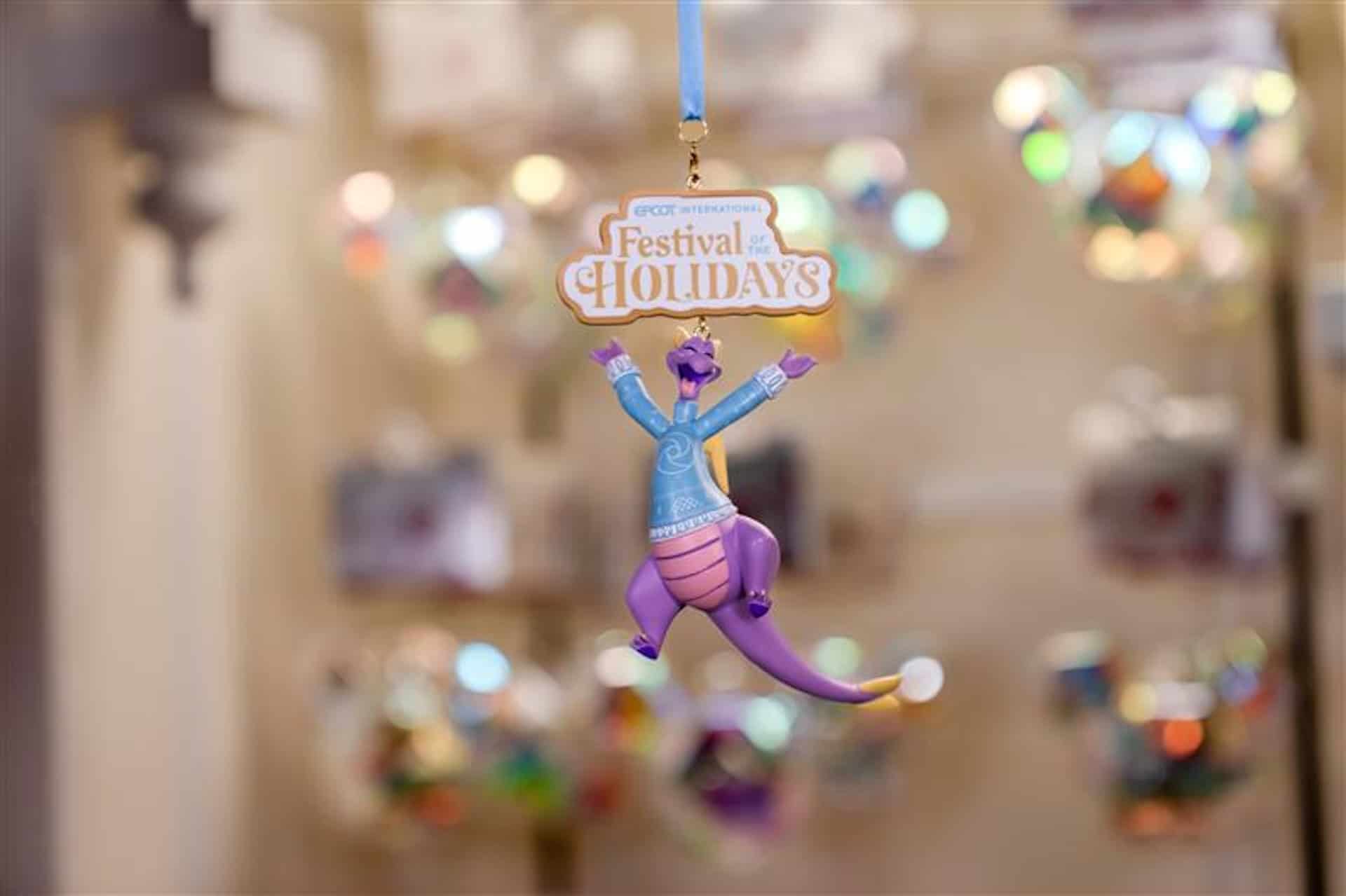 an ornament with Epcot International Festival of the Holidays wording and Figment figurine wearing a blue ugly sweater 