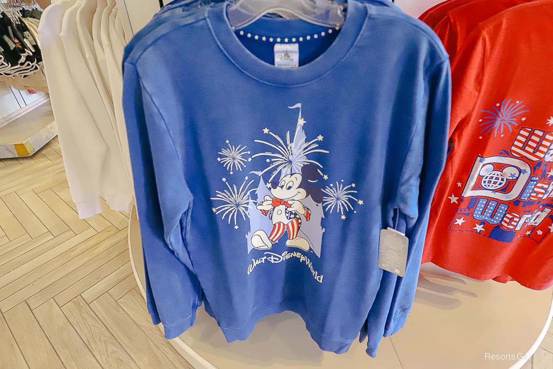 a blue sweatshirt with the WDW logo and Mickey Mouse in a 4th of July outfit