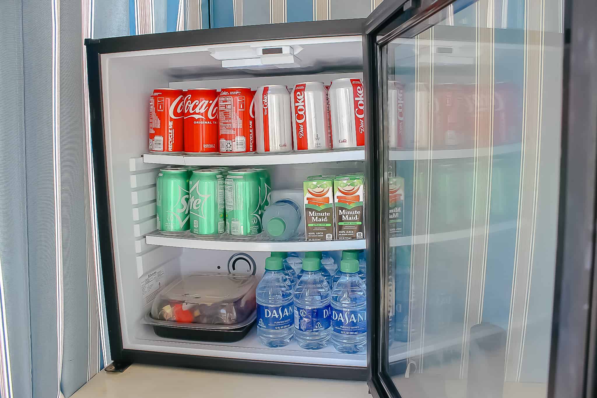 A mini fridge at the Stormalong Bay Cabana stocked with sodas, juice, water, and fruit. 