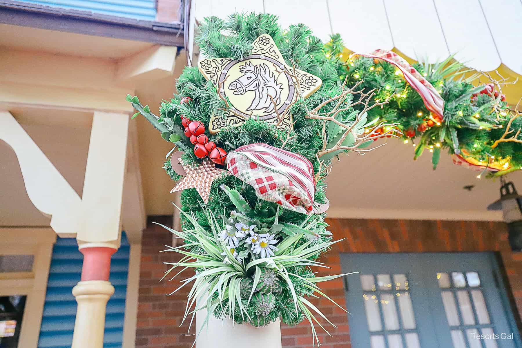 a star with a horse in the center of it and red bells wrapped with other items in the garland 