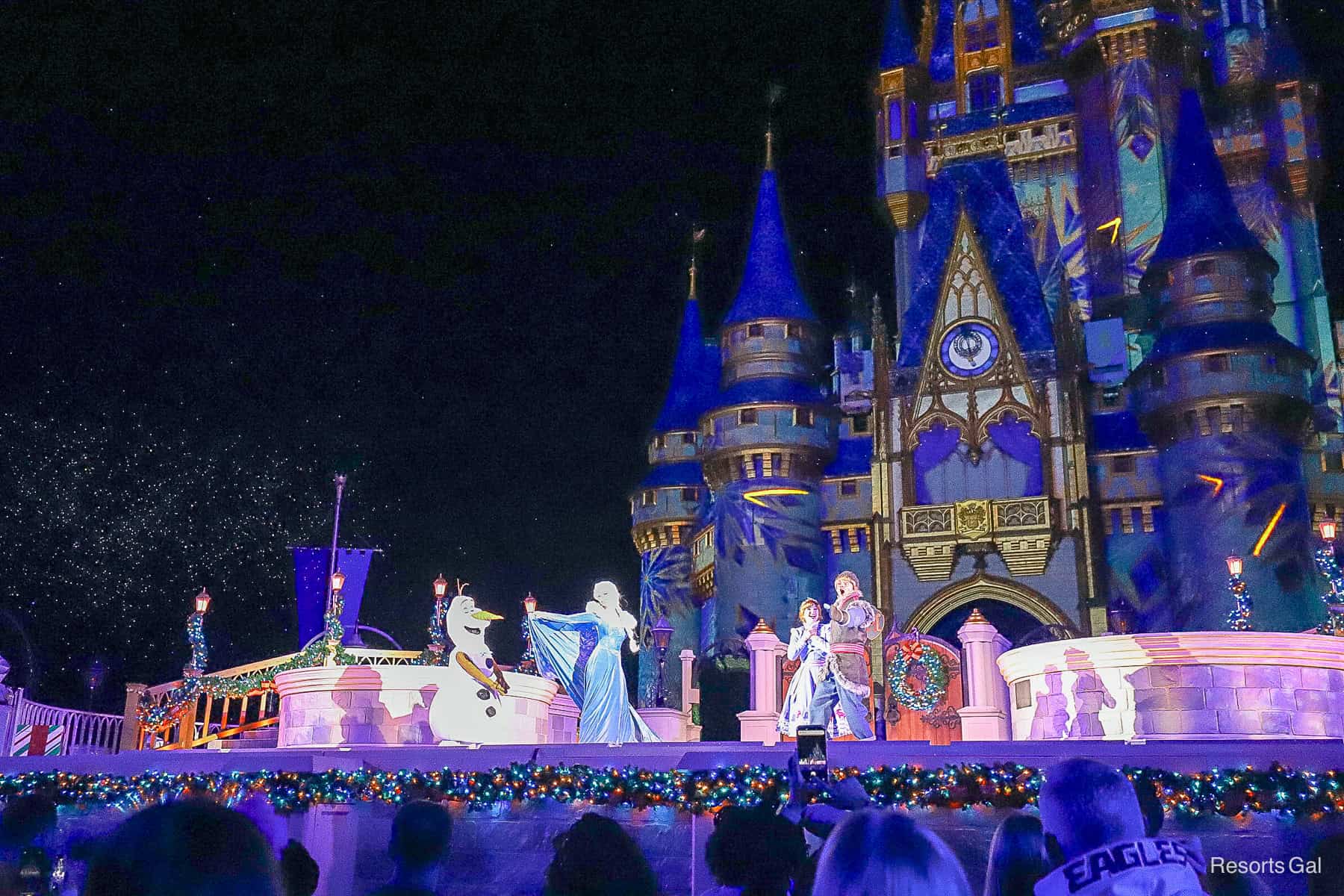 Olaf, Anna, Kristoff, and Elsa on stage at Cinderella Castle for the Christmas castle lighting