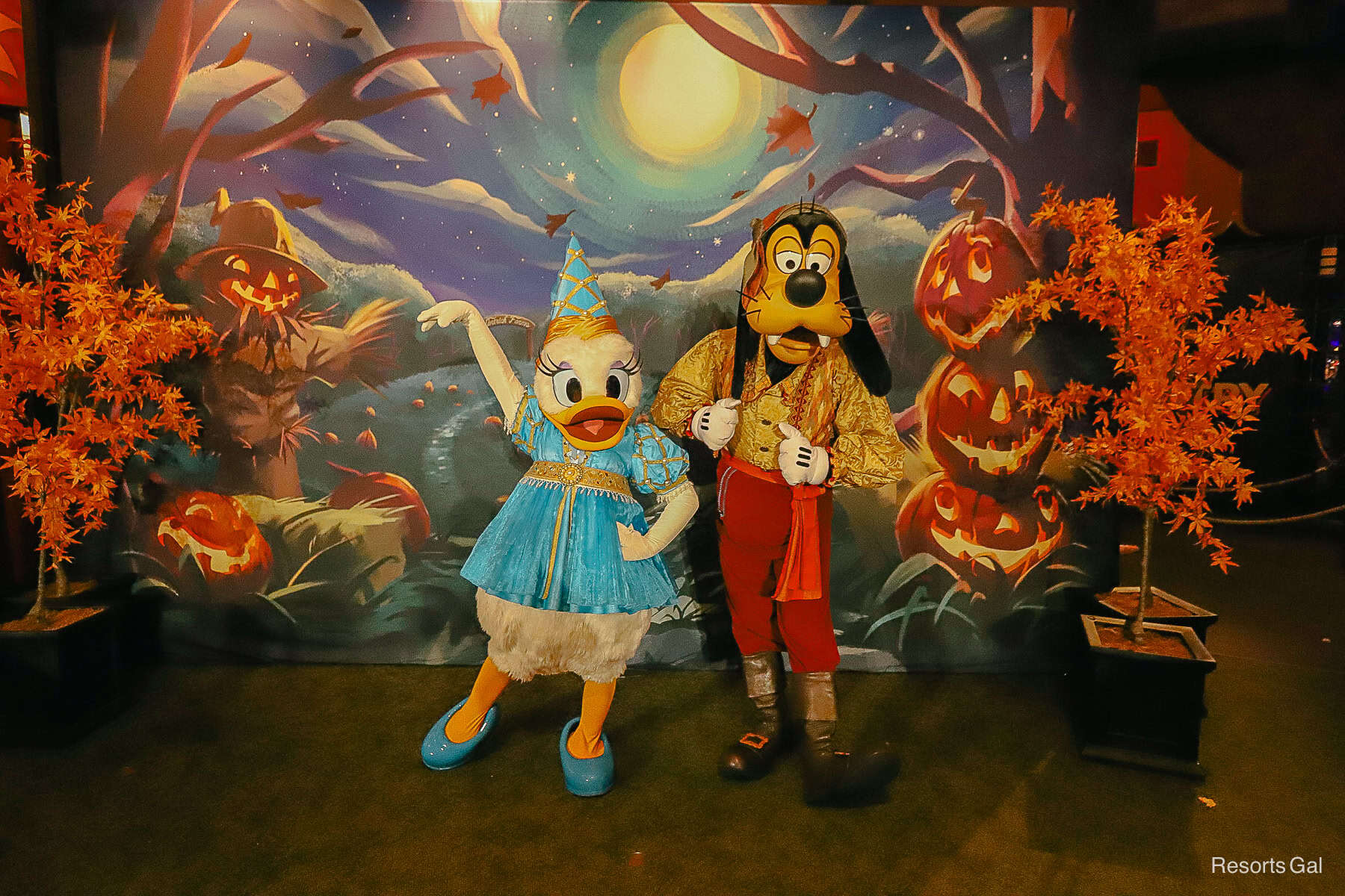 Goofy poses with hands on vest and Daisy Duck with arm in air 