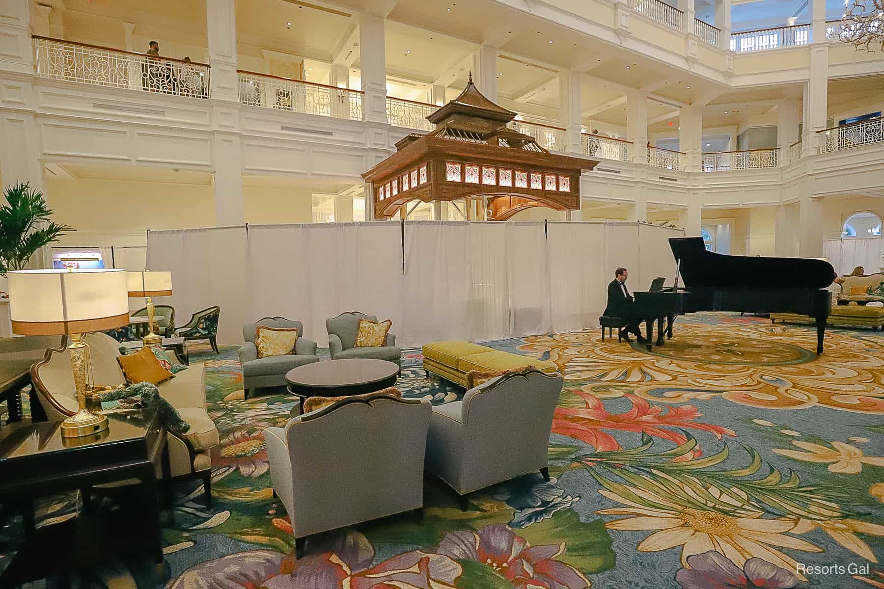 a view of the piano player in the lobby in front of the partially curtained bar 