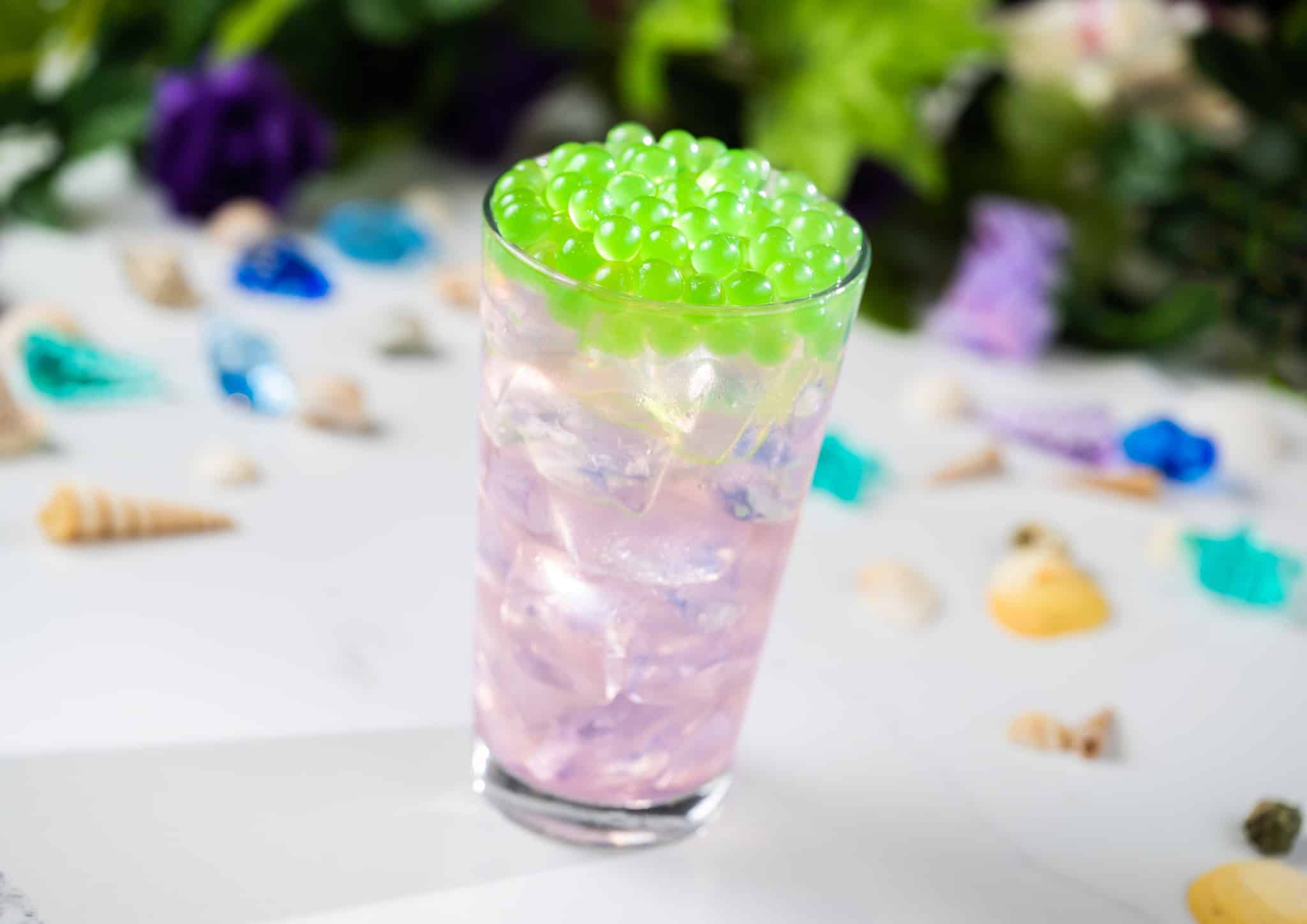 an iridescent drink with green boba pearls 