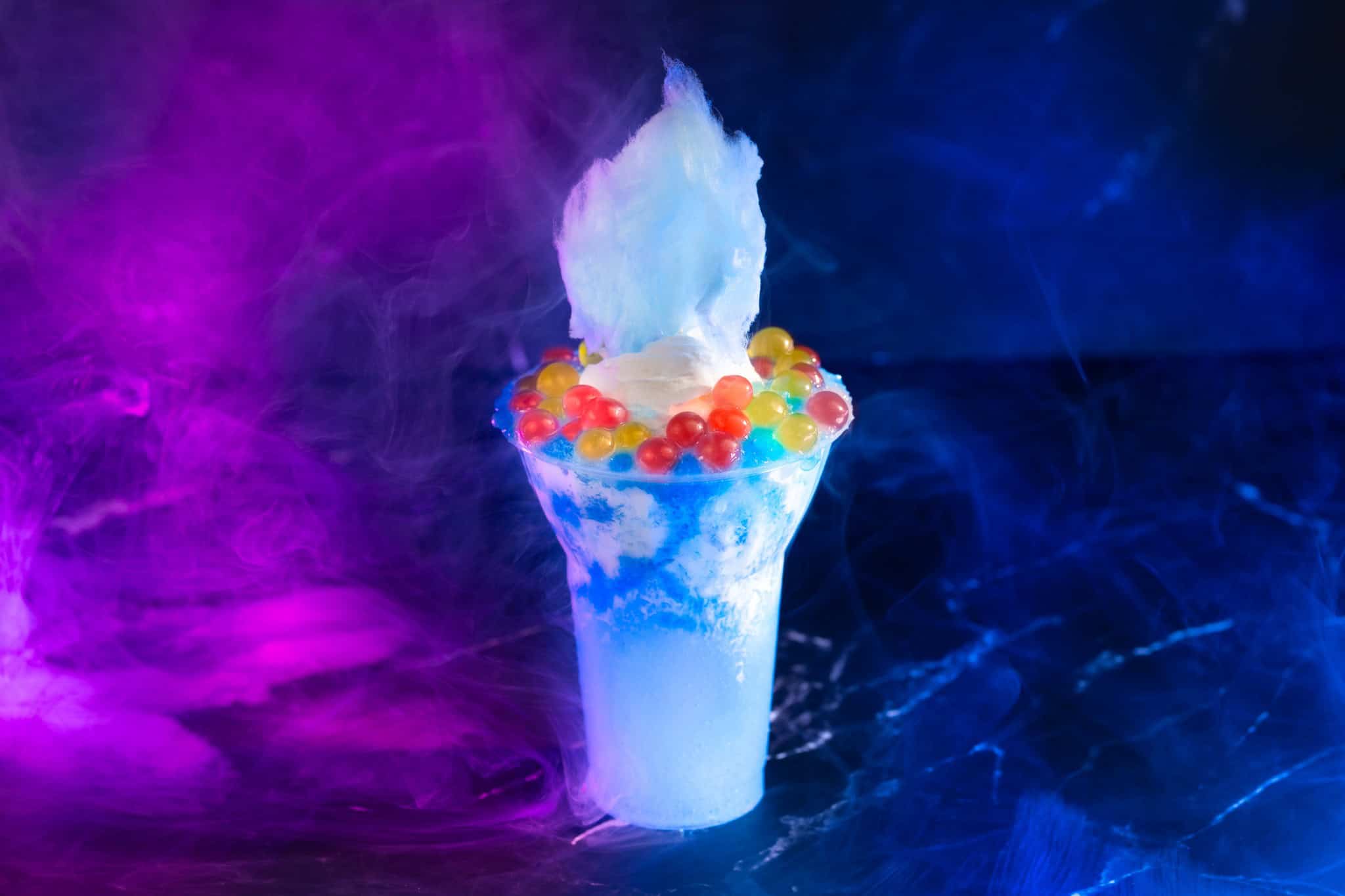 a blue slushy and vanilla ice cream float with bright boba balls and cotton candy top