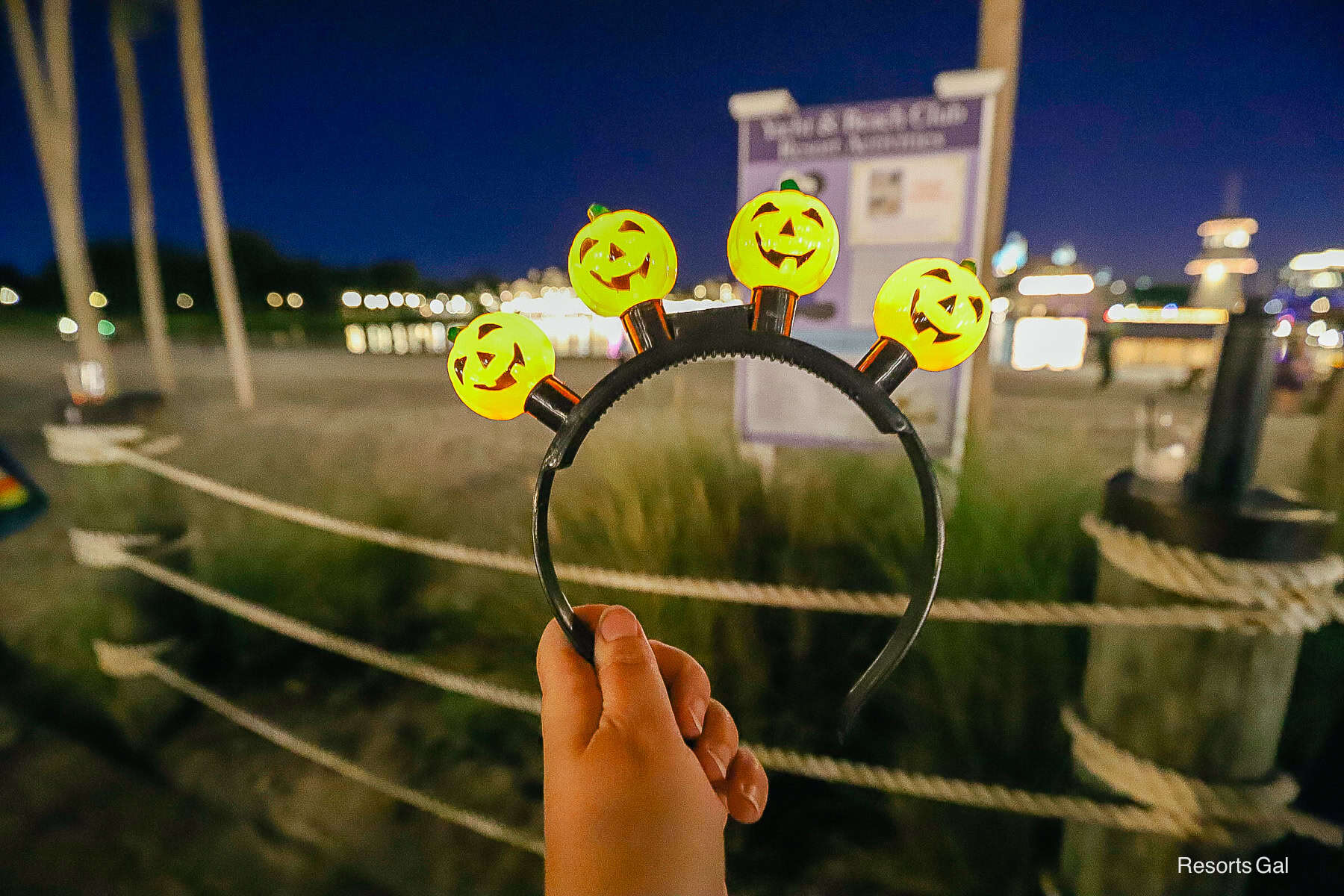 a hand holding a pumpkin glow headband for Halloween at the Disney Hotels