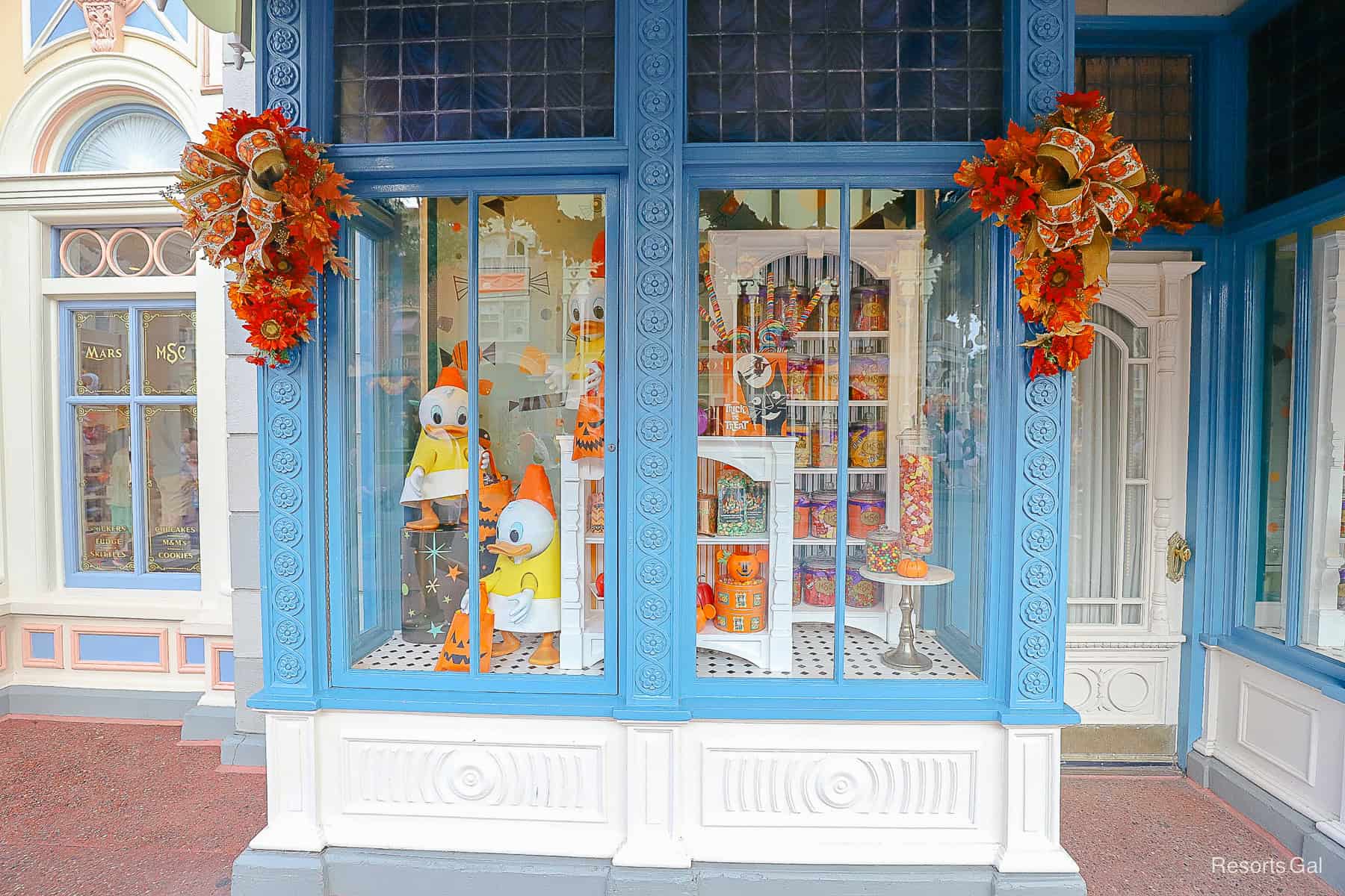 a shop window with Donald Duck's nephews in Halloween costume like candy corn 