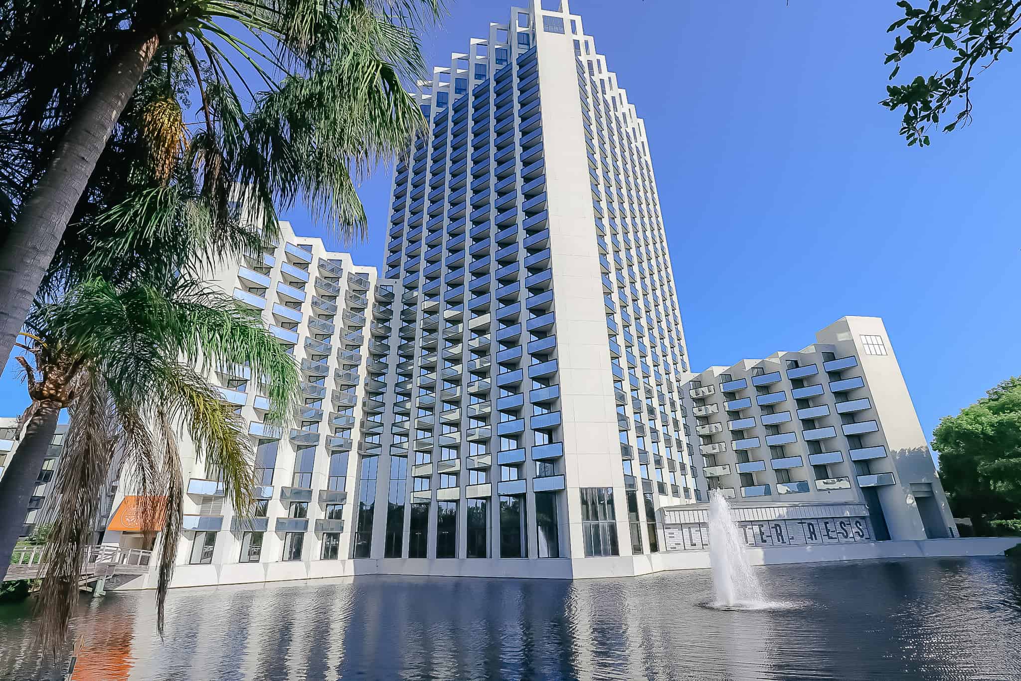 The Buena Vista Palace Hotel as seen from behind a water fountain with the glass windows reflecting the sky. 