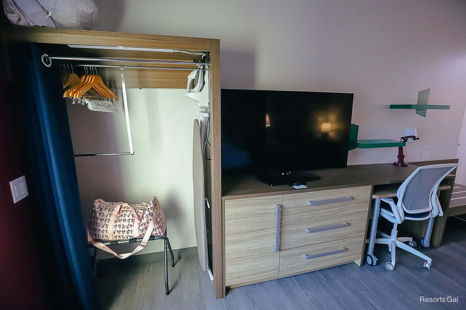 a closet, iron, ironing board and television area 
