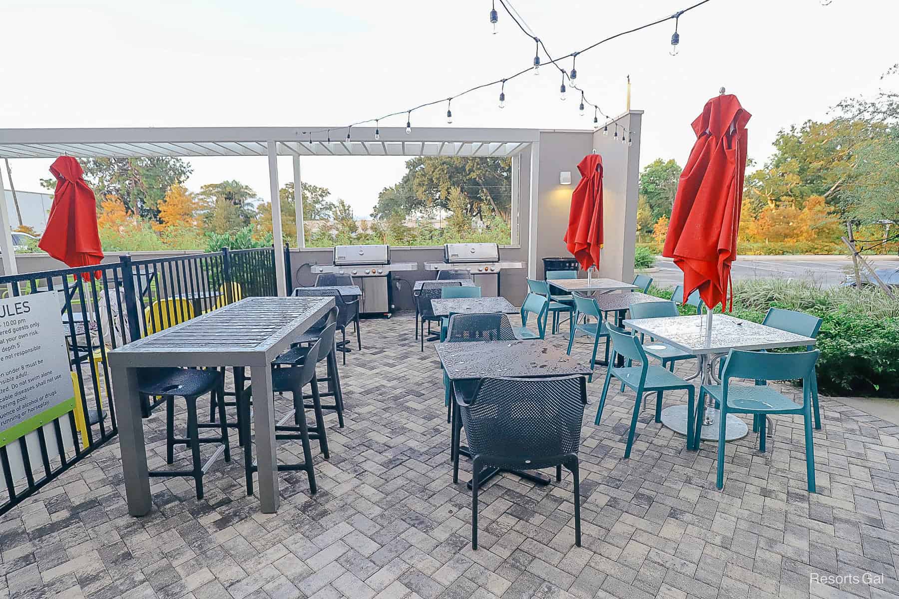 a seating area with tables and umbrellas and grills 