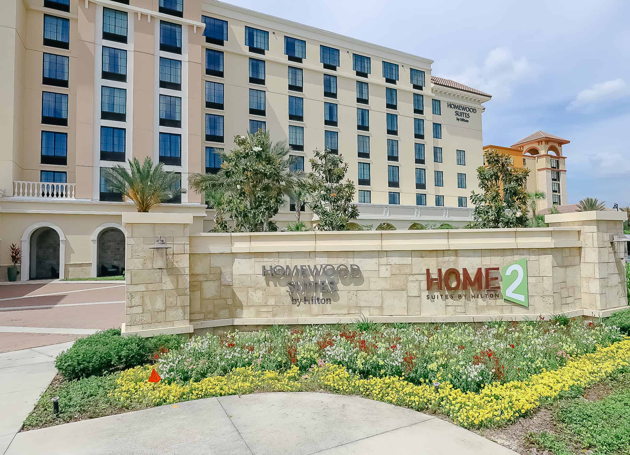 Hotel entrance with flowers mixed in the landscaping. 