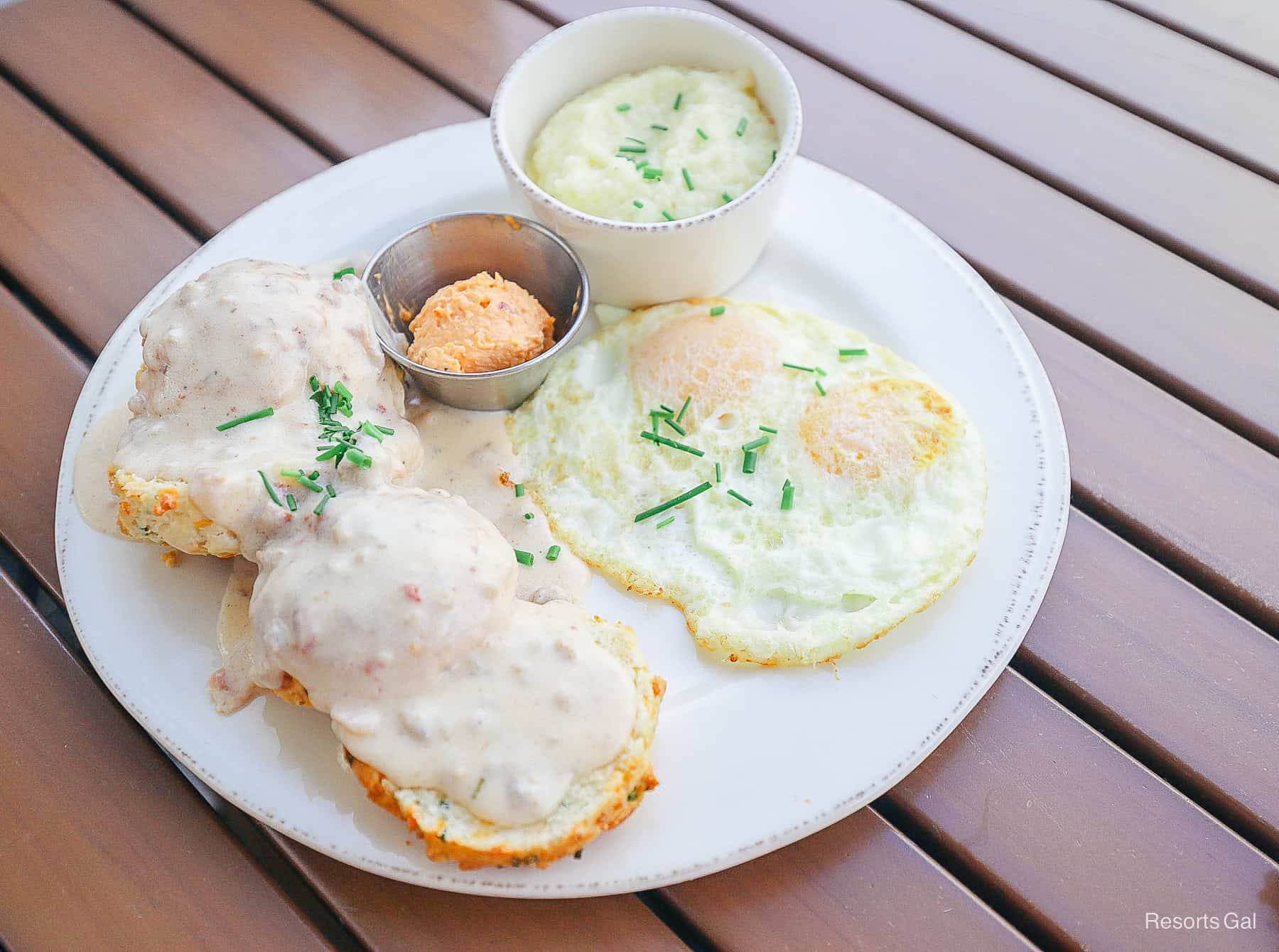 a plate with biscuits, gravy, eggs, and grits 