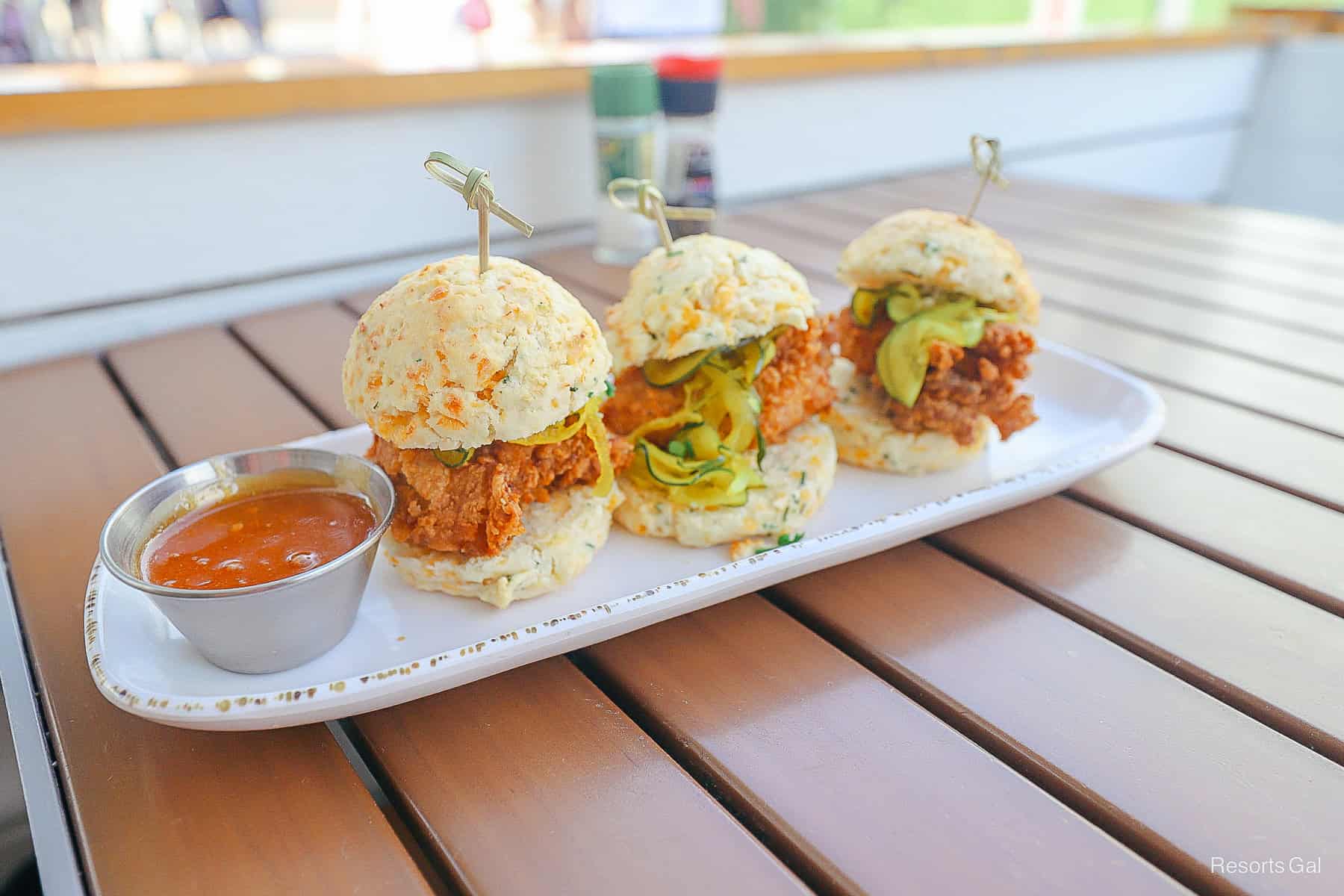 a side of hot honey with chicken biscuits topped with pickles 