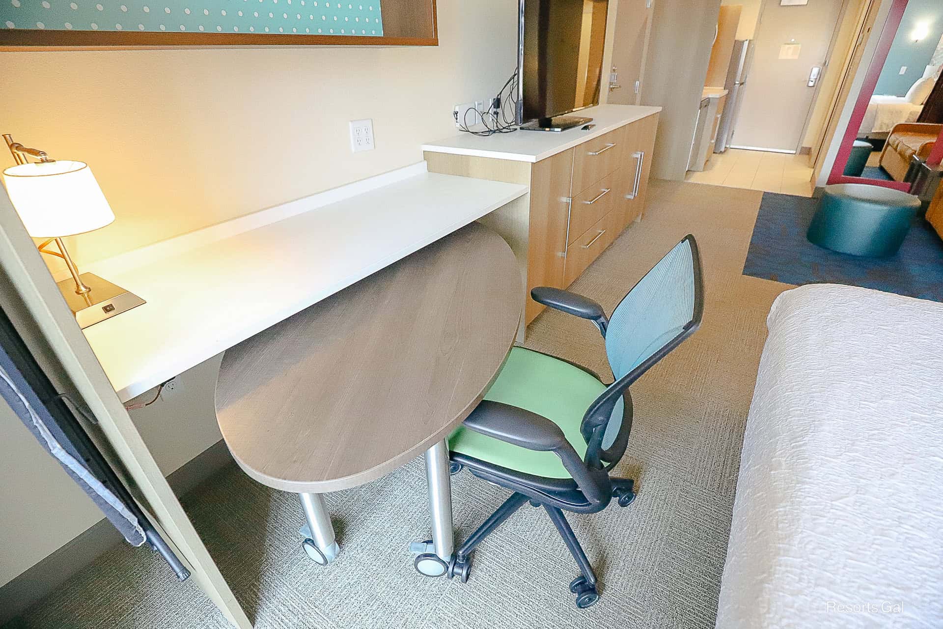 a roll out desk with chair in the hotel room