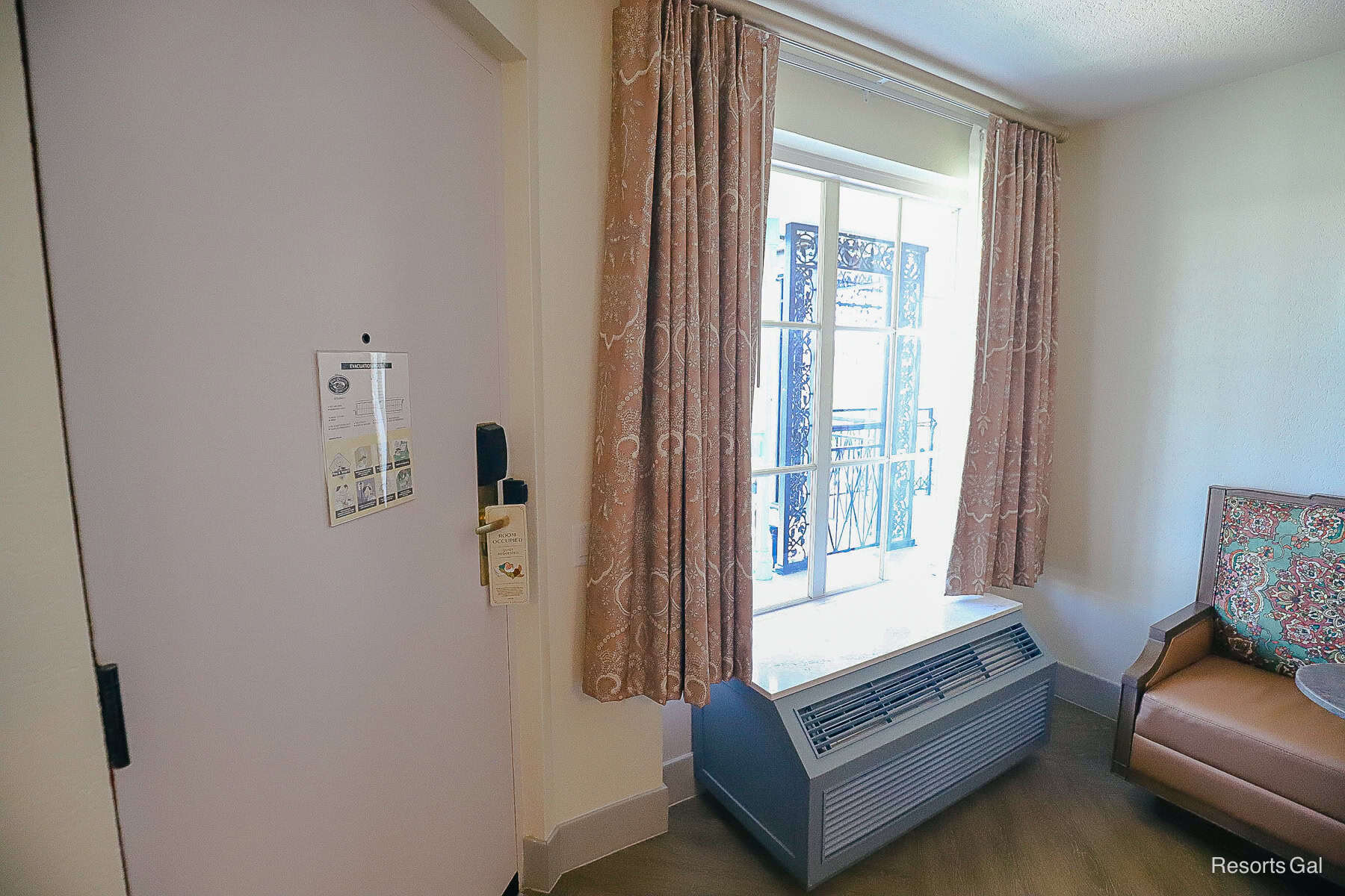 the door, window, and air conditioning unit at the front of the room