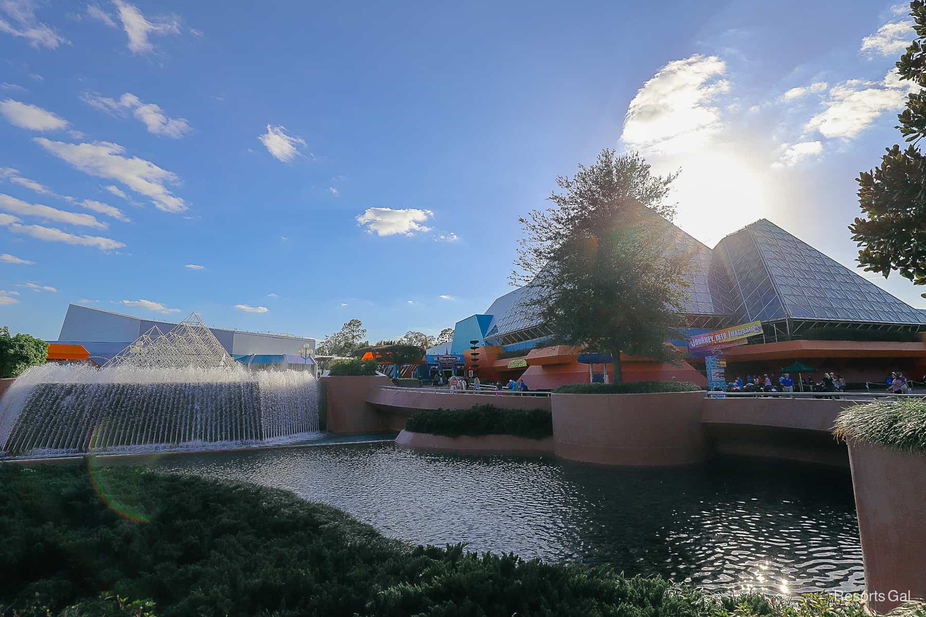 shows the Imagination Pavilion before sunset with the fountains to the left and pyramid to the right 