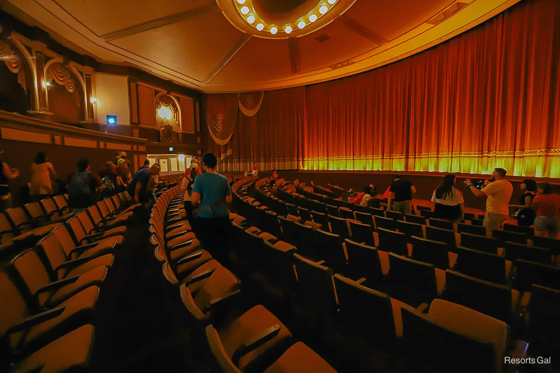 theater seating with red and gold curtains over the screen 