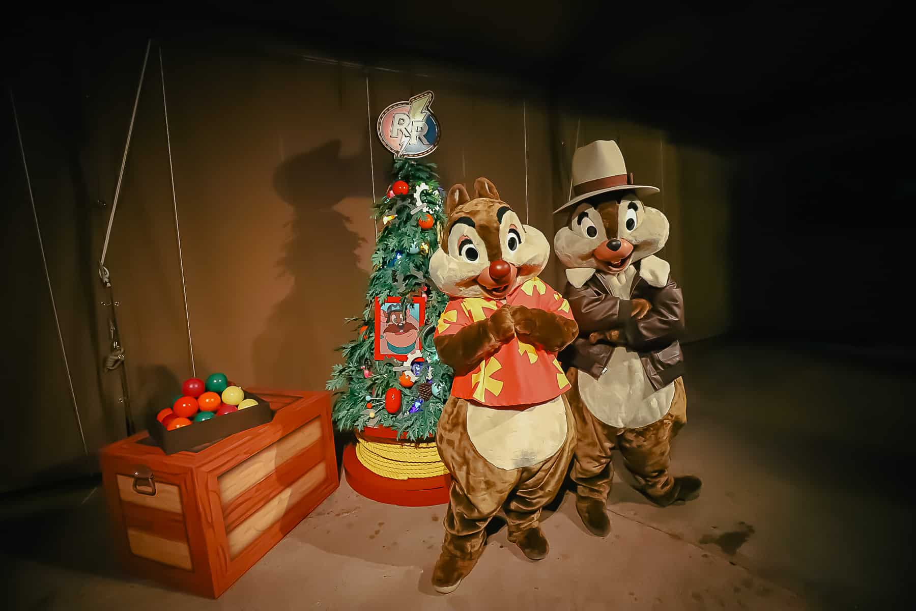 Chip and Dale pose in front of a set with a Christmas tree topped with a RR decoration for Rescue Rangers. 