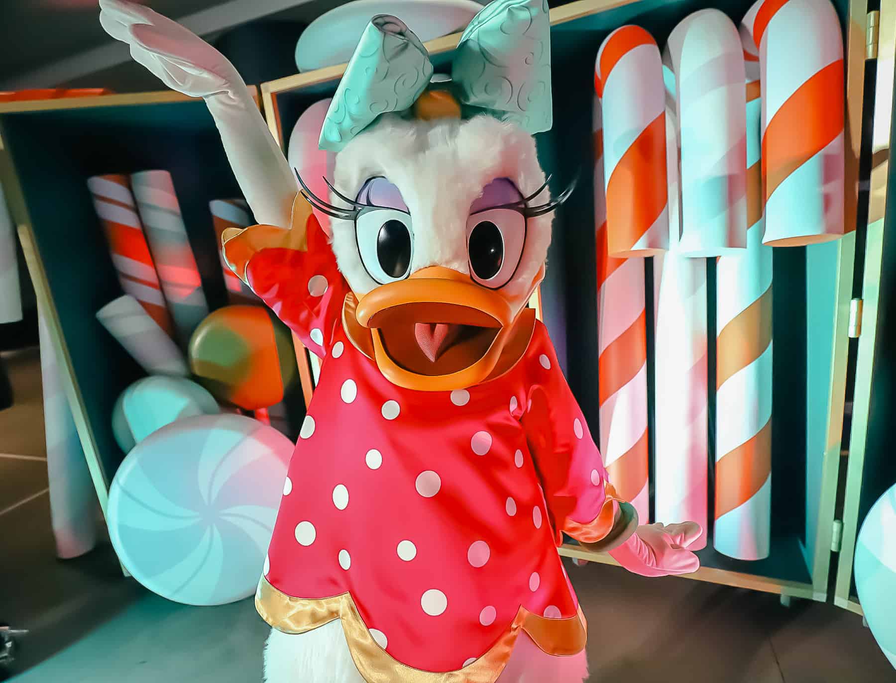 Daisy Duck poses like a diva with a hot pink dress with white polka dots and a mint green bow. 