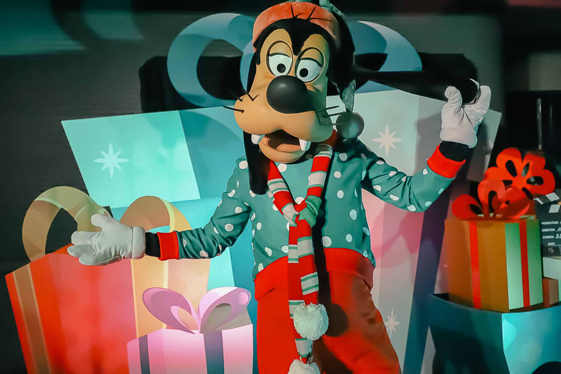 Goofy is wearing a green sweater, scarf, and Santa Hat for Jollywood nights. 