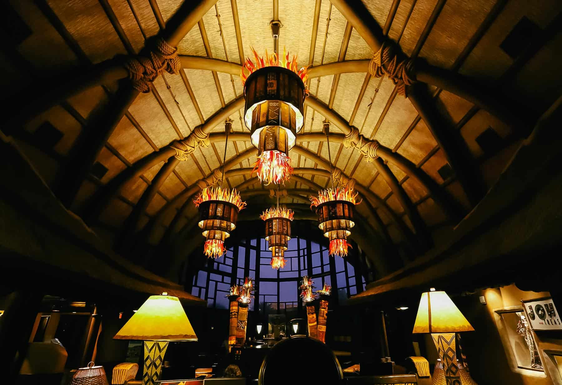 the Kidani Village lobby at night is stunning with light fixtures of blown glass that look like yellow, red, and orange flames 