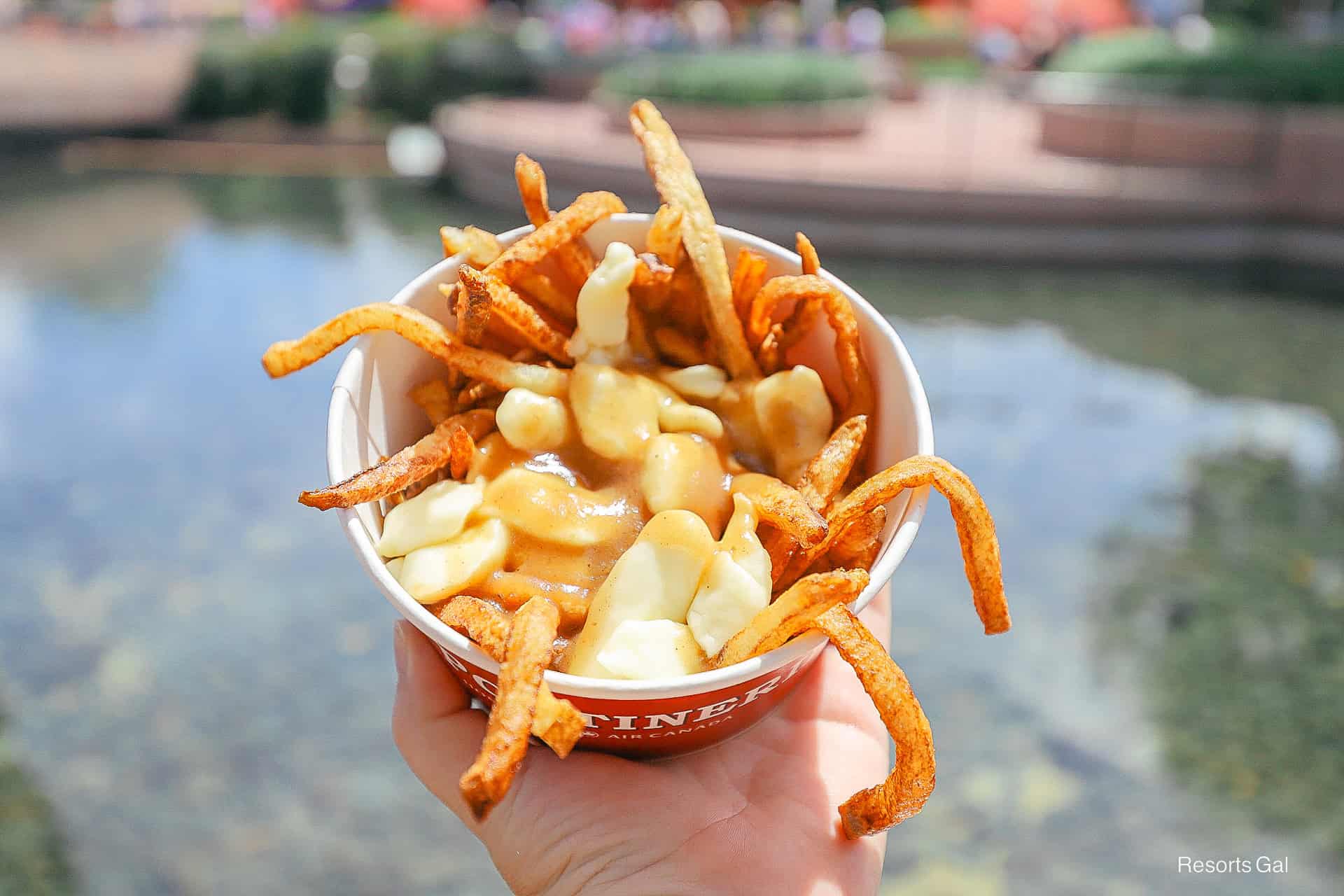 holding an order of La Poutinerie fries up at Epcot
