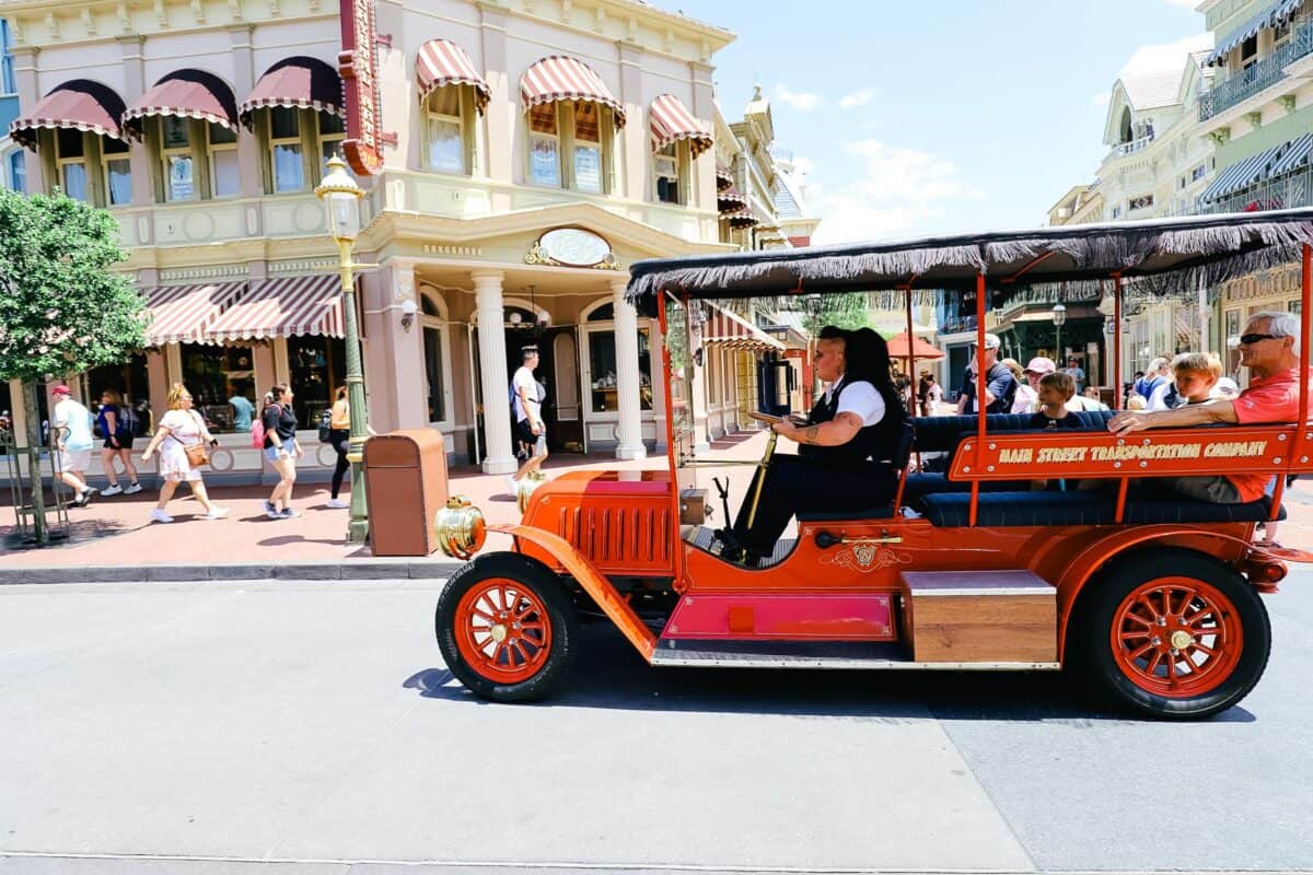 A cast member drives guests down Main Street in one of the Main Street Vehicles.