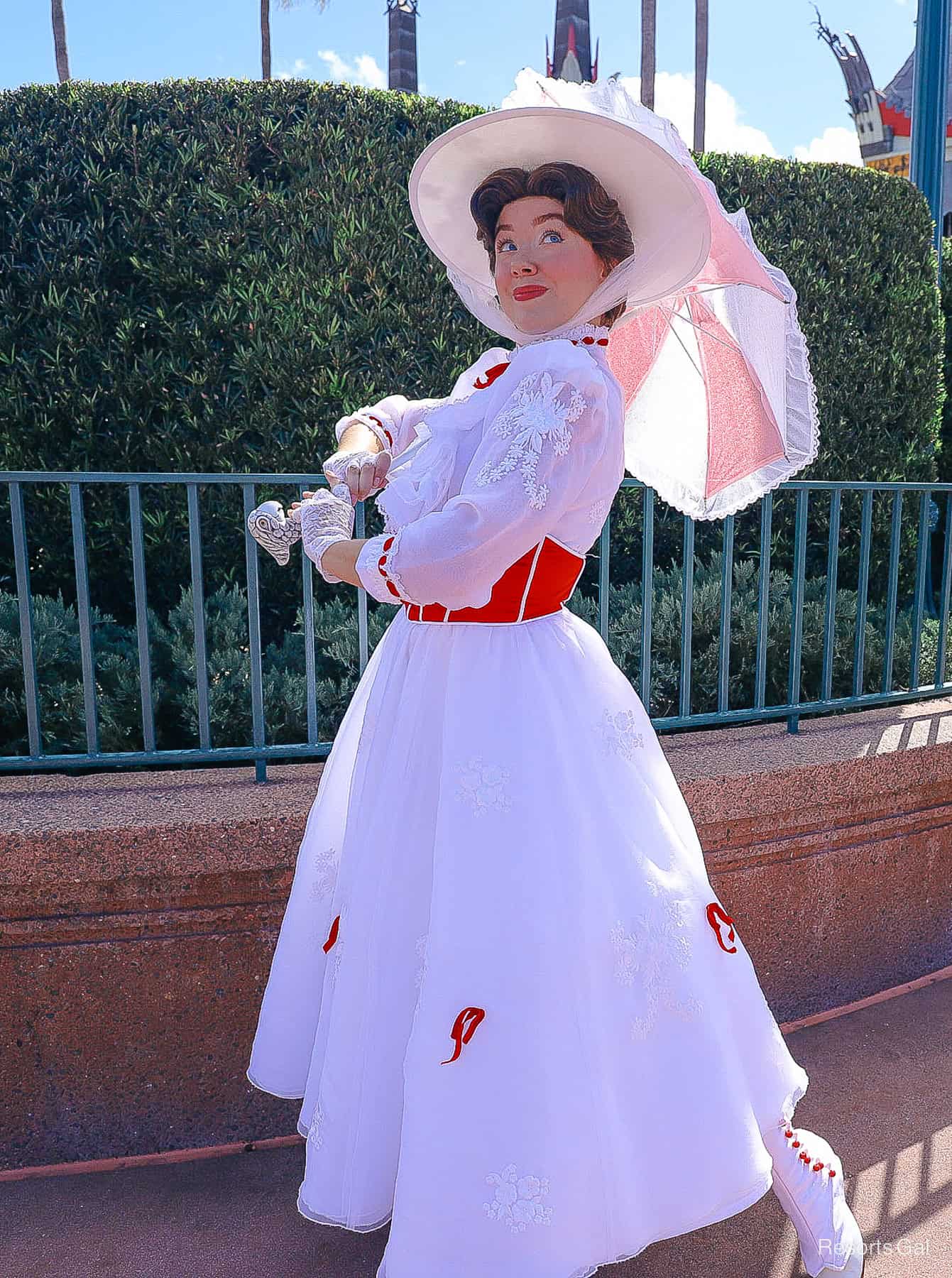 Mary Poppins standing in front of a hedge with her umbrella out , full vertical image 